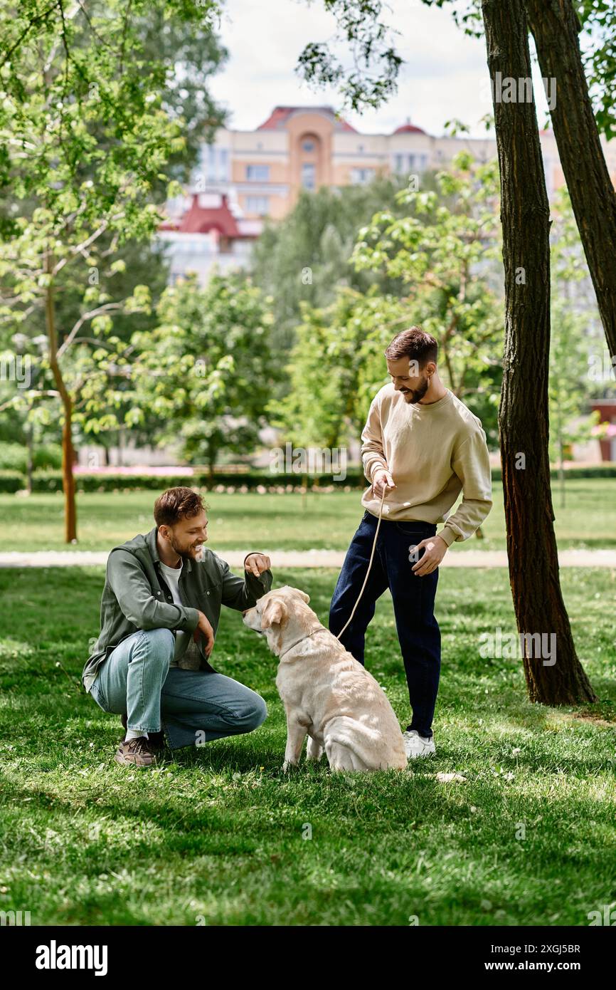 Un couple gay profite d’un après-midi ensoleillé dans le parc avec leur labrador retriever. Banque D'Images