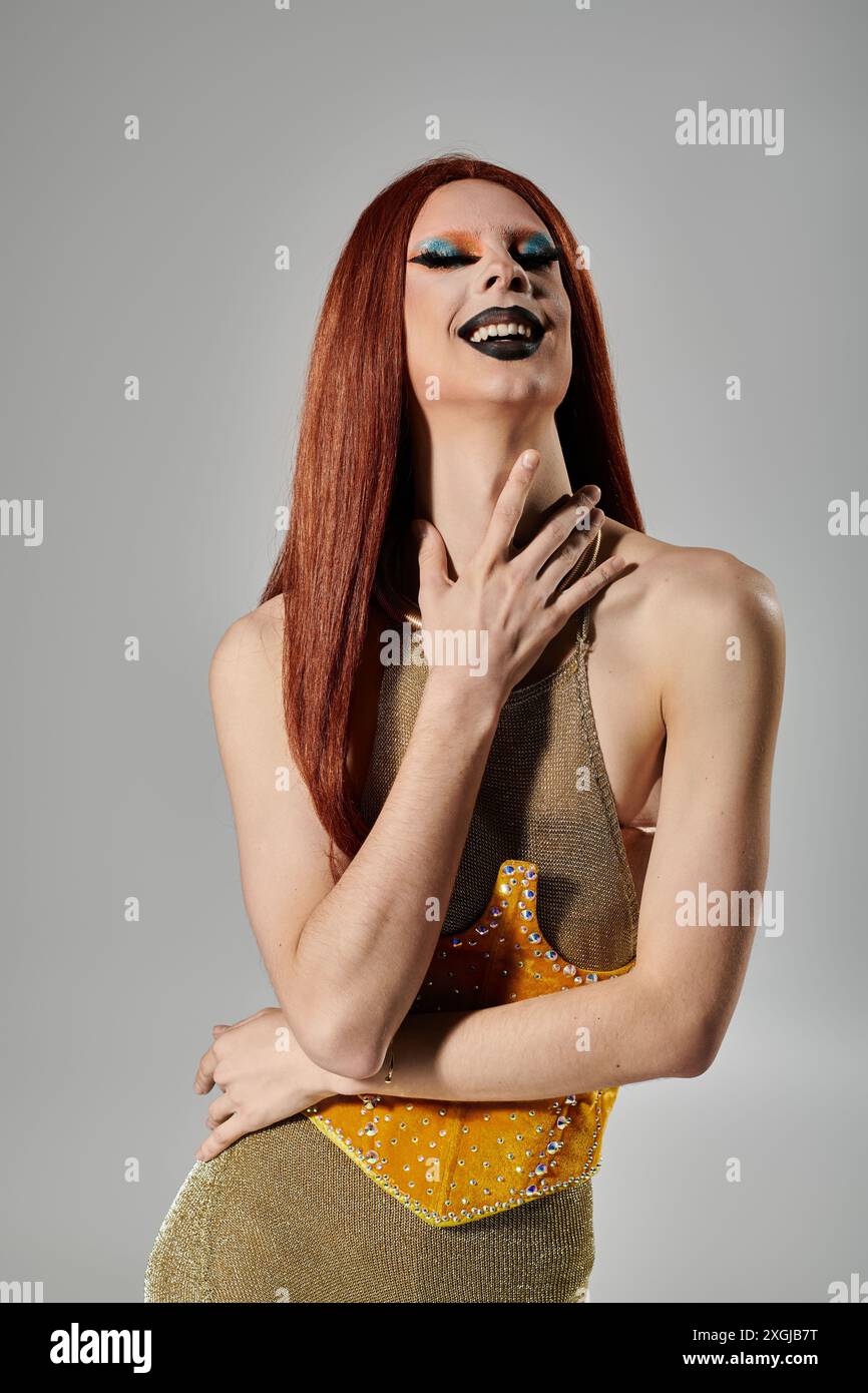 Une drag queen dans une robe dorée étincelante rit de joie. Banque D'Images