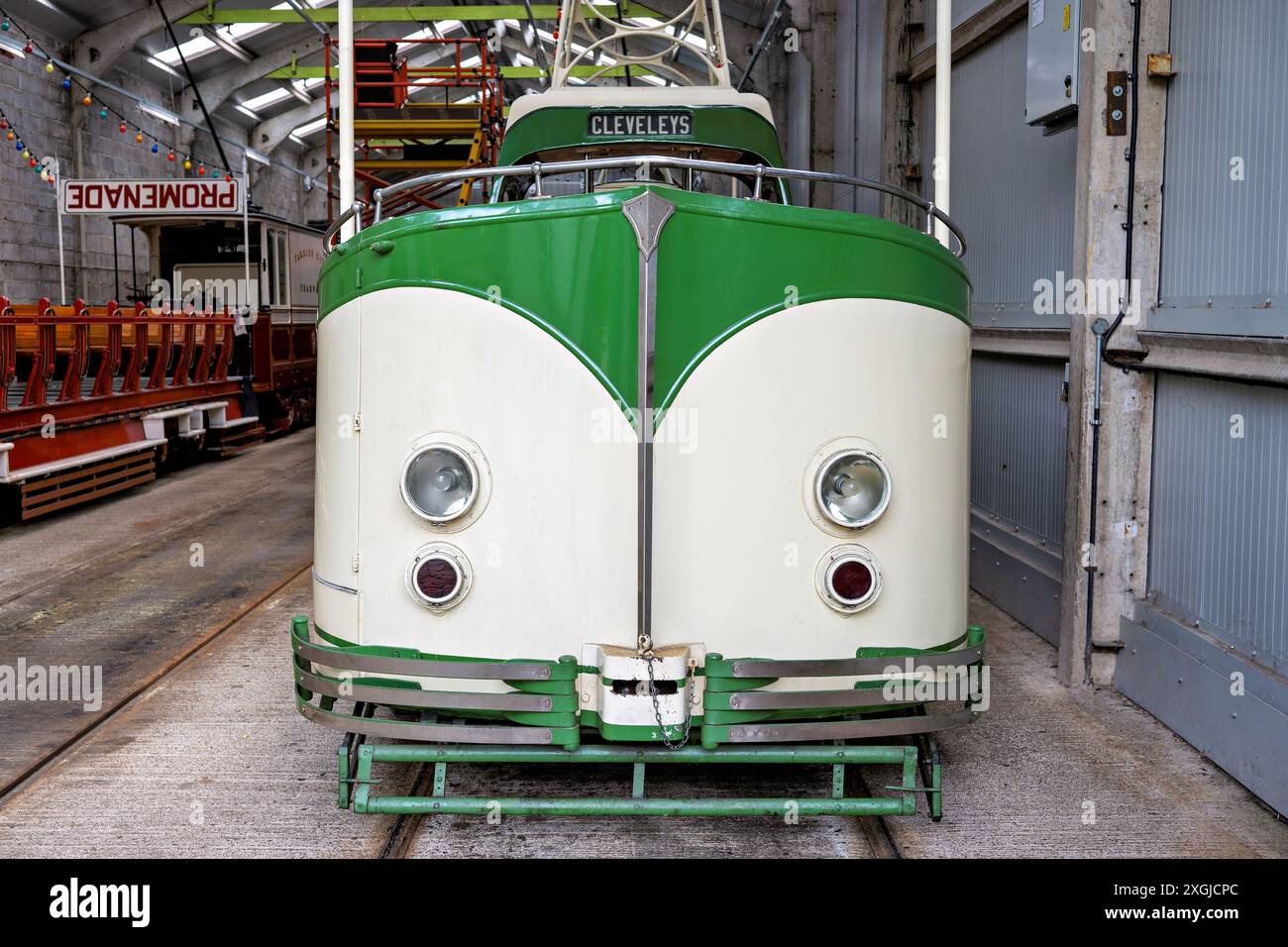 Tramway vert et blanc vintage dans un dépôt de tramways historique Crich Derbyshire UK avec les vieux tramways environnants sous éclairage intérieur. Banque D'Images