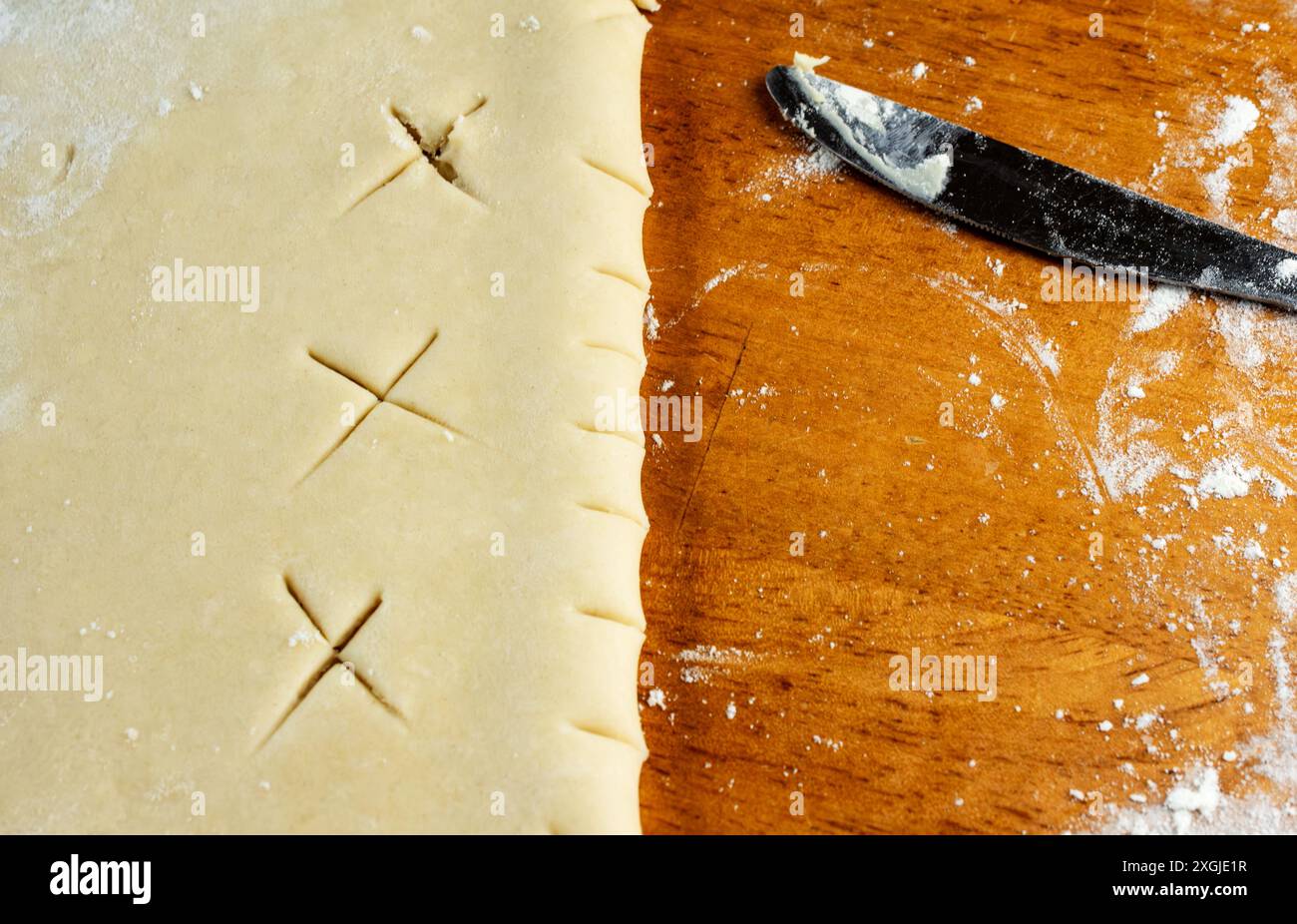 Faire une tarte : croûte supérieure. Une fois la croûte supérieure déroulée, elle est pliée et un couteau est utilisé pour créer des trous d'aération dans la pâte. Banque D'Images
