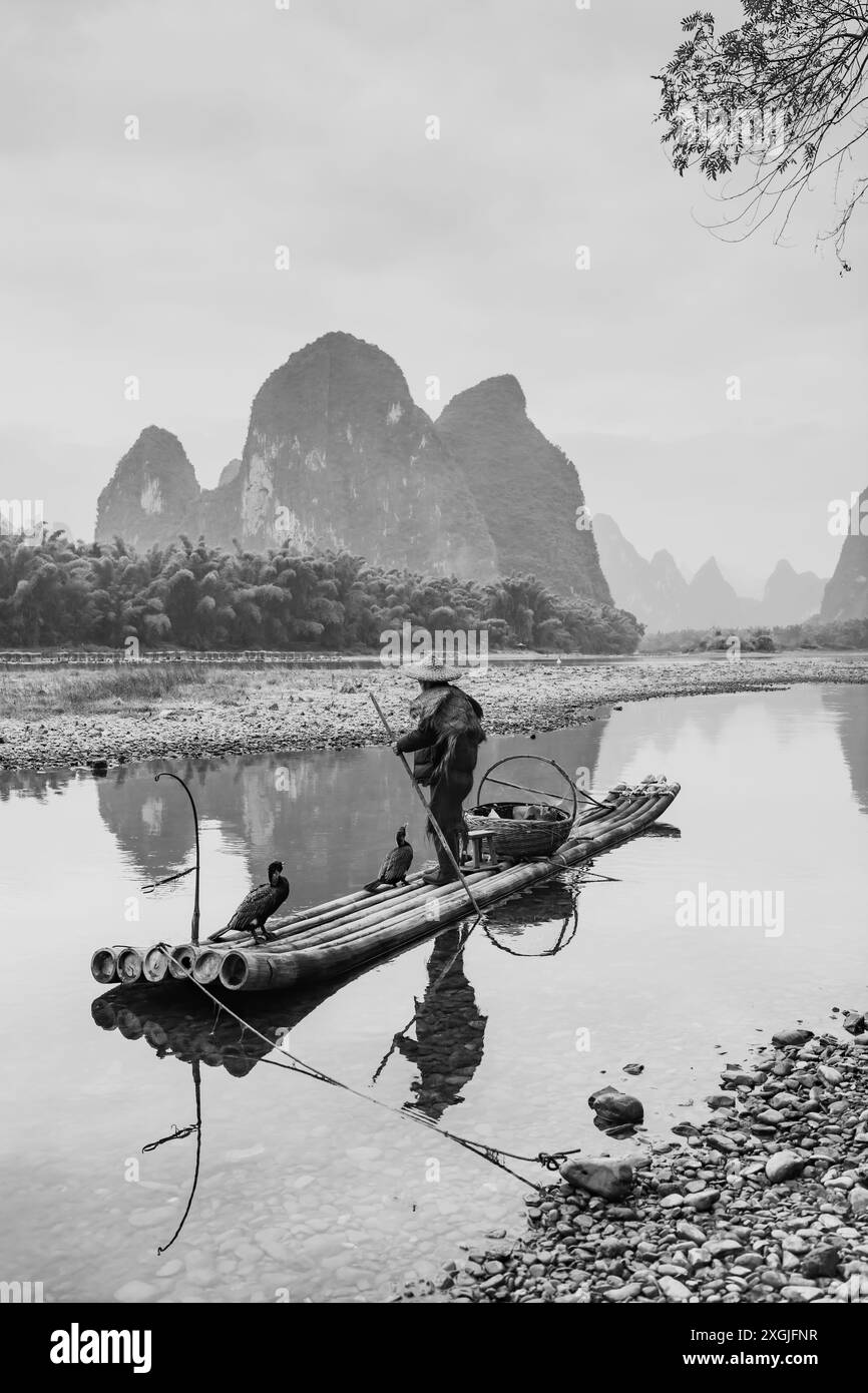 Pêcheur cormoran et son oiseau sur la rivière Li à Yangshuo, Guangxi, Chine. Ciel de coucher de soleil avec espace de copie pour le texte Banque D'Images