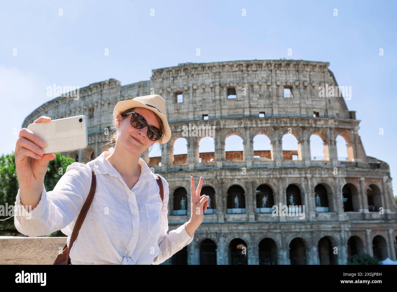 Heureuse jeune femme prenant un selfie devant le colisée pendant son séjour à Rome, en Italie Banque D'Images