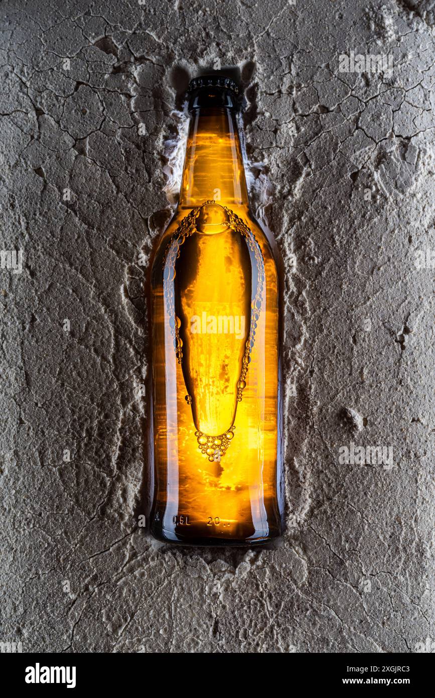 Une bouteille en verre avec une boisson brise le sol. Fissures dans le sol d'une bouteille. Banque D'Images