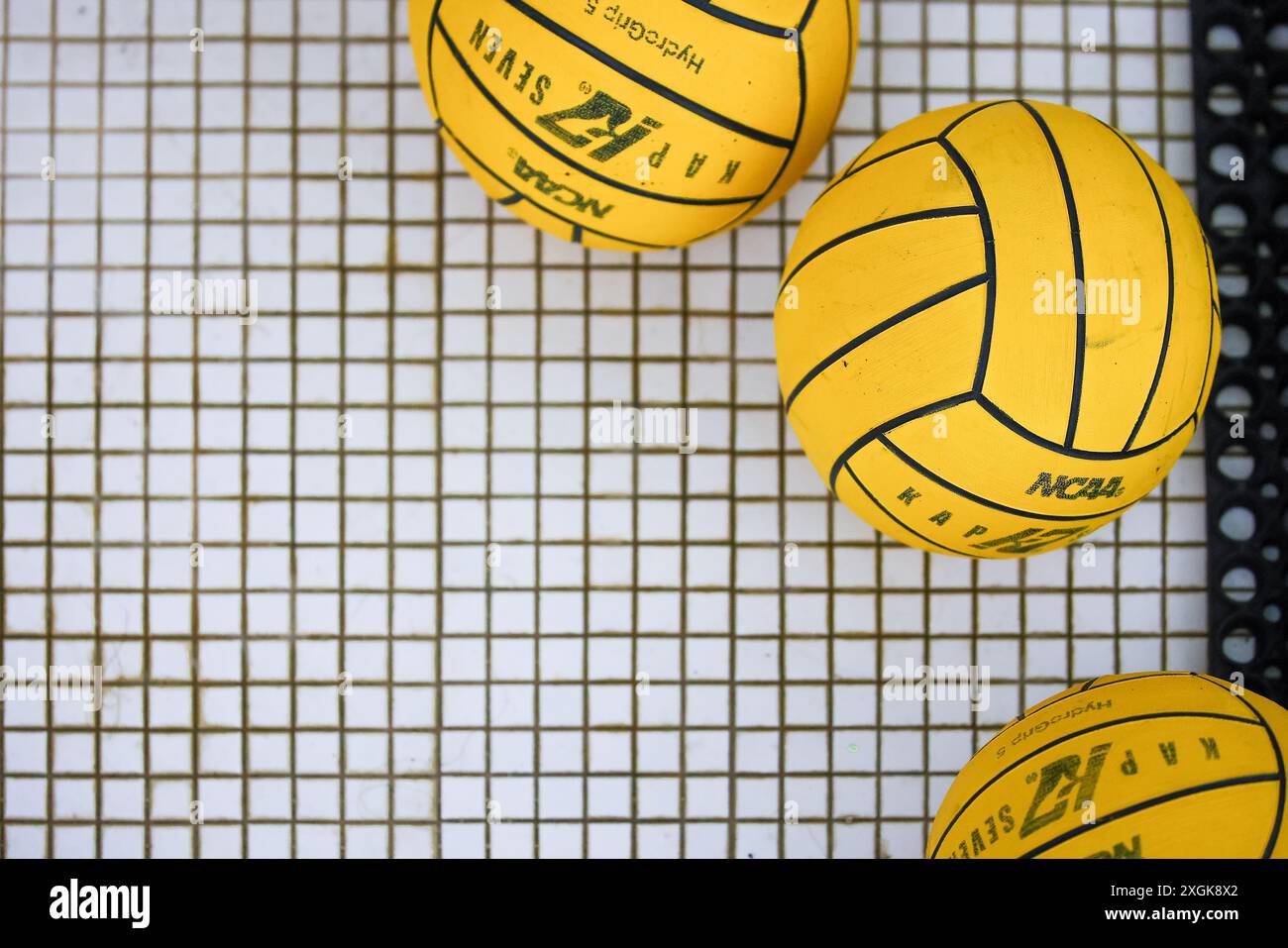 Trois balles de water-polo au bord d'une terrasse de piscine. Banque D'Images