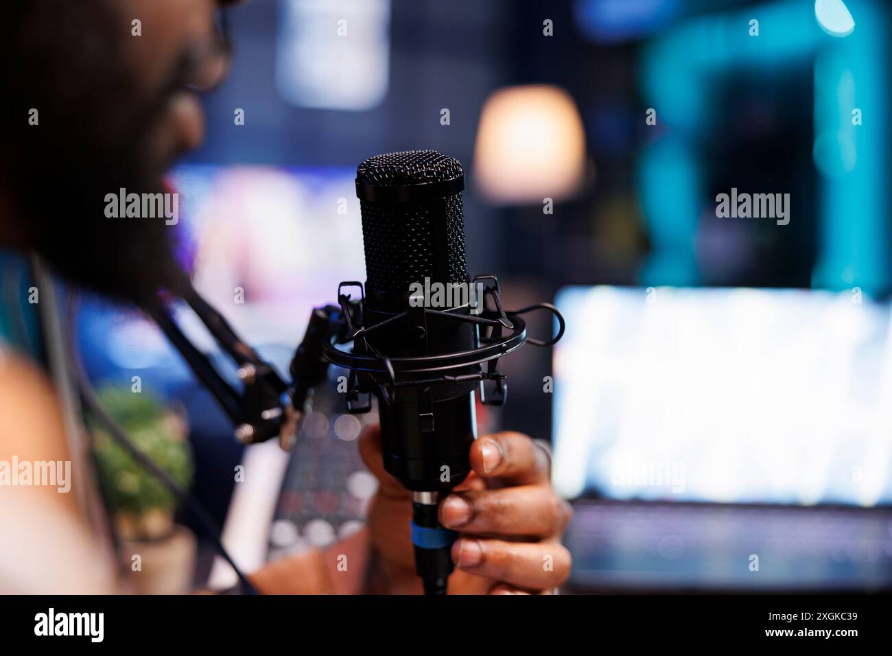 Le présentateur masculin enregistre un spectacle de chat en direct à la maison avec un équipement audio de qualité. Homme afro-américain parle dans un microphone lors d'une production sur Internet pour un épisode de podcast. Banque D'Images