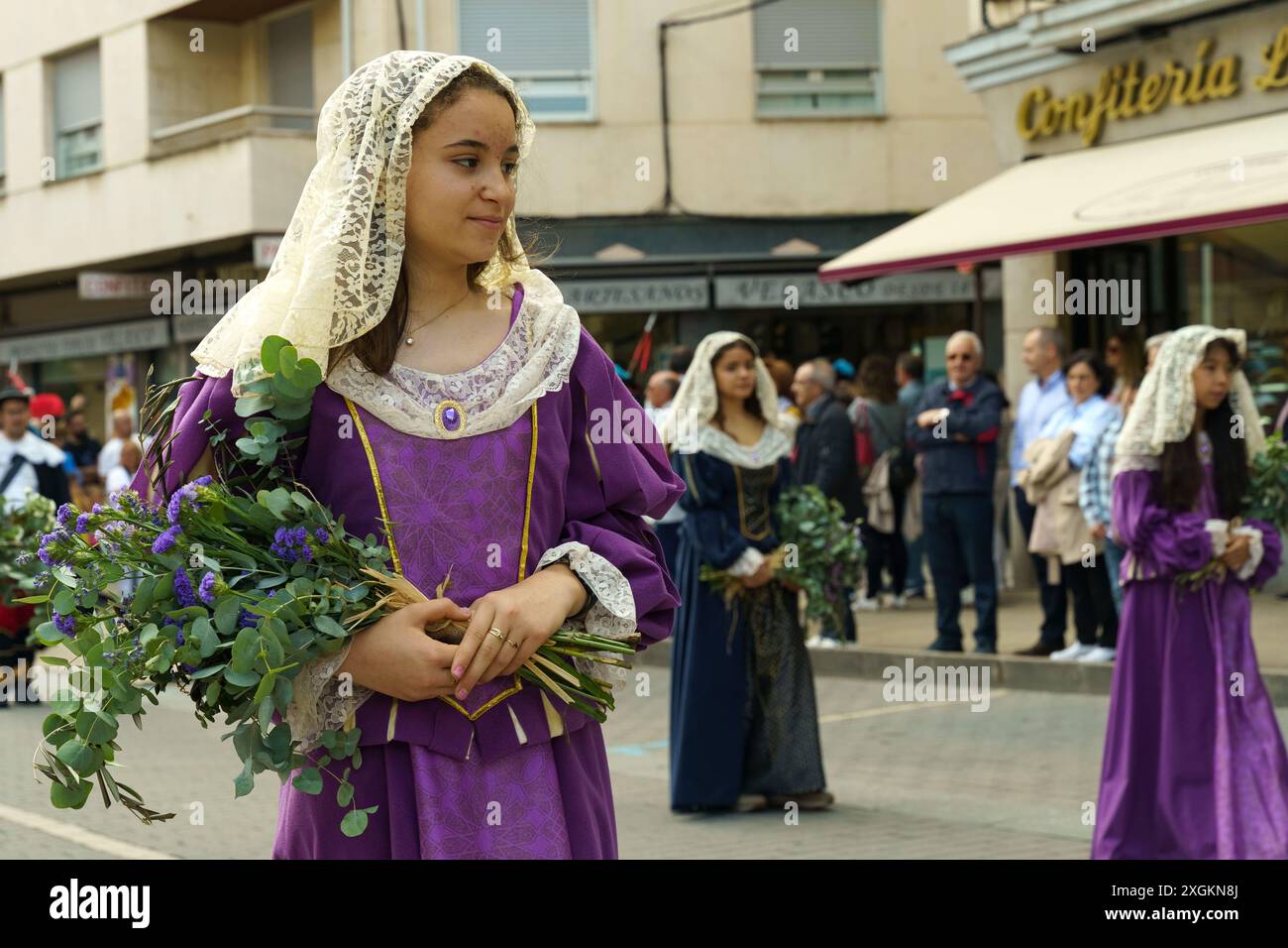 Astorga, Espagne - 4 juin 2023 : une jeune femme en robe traditionnelle espagnole en dentelle tient un bouquet de fleurs tout en marchant dans un défilé à travers le stre Banque D'Images