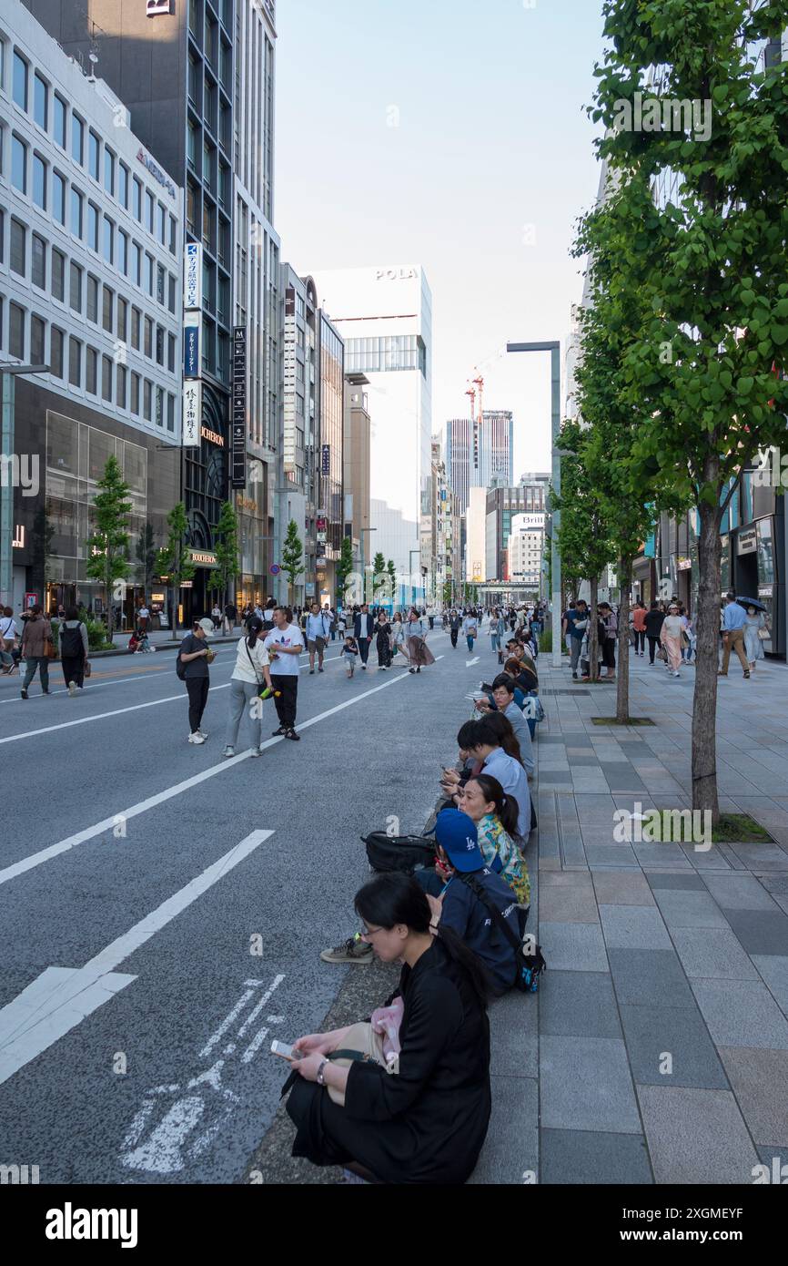 Un samedi animé à Ginza, Tokyo, les rues sont fermées à la circulation, permettant aux gens de se détendre et de profiter de l'atmosphère vibrante au milieu de la construction moderne Banque D'Images