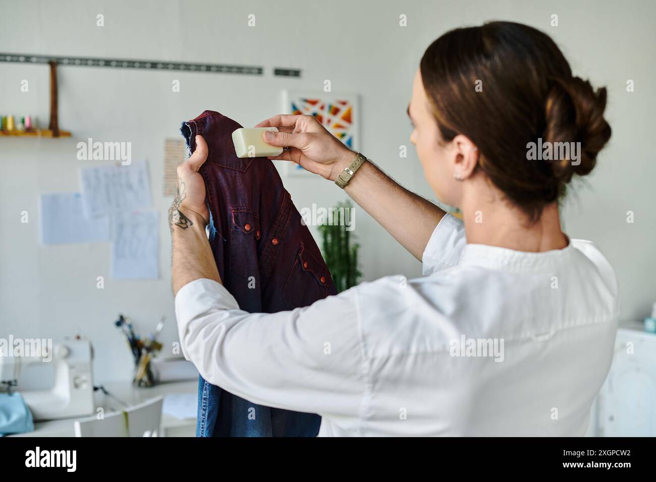 Un jeune homme applique méticuleusement du savon sur un vêtement dans son atelier de restauration de vêtements de bricolage, insufflant une nouvelle vie aux vêtements jetés. Banque D'Images