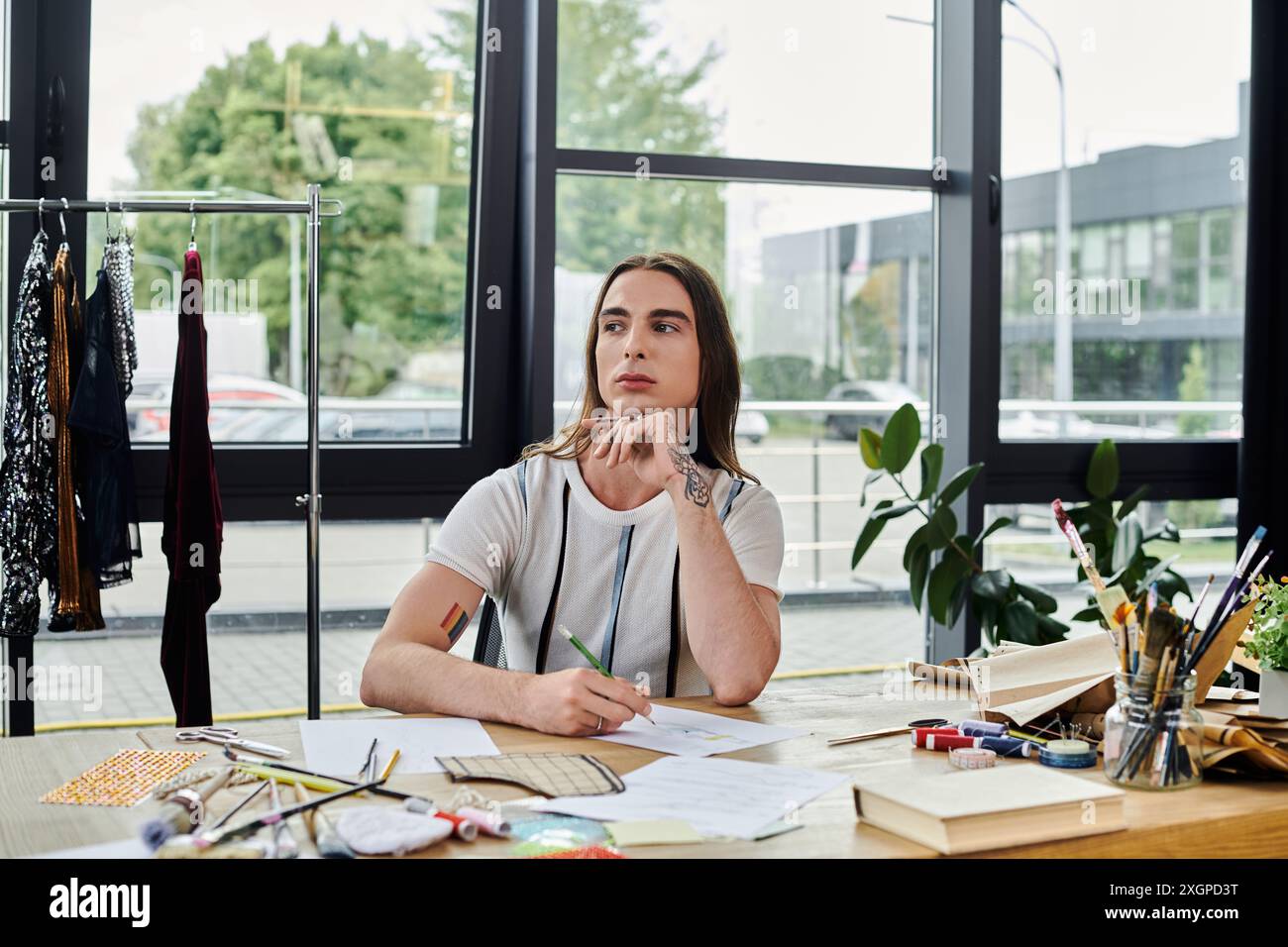 Un jeune homme travaille sur un projet de design dans son atelier de restauration de vêtements. Il se concentre sur la durabilité, donnant une nouvelle vie à de vieux articles. Banque D'Images