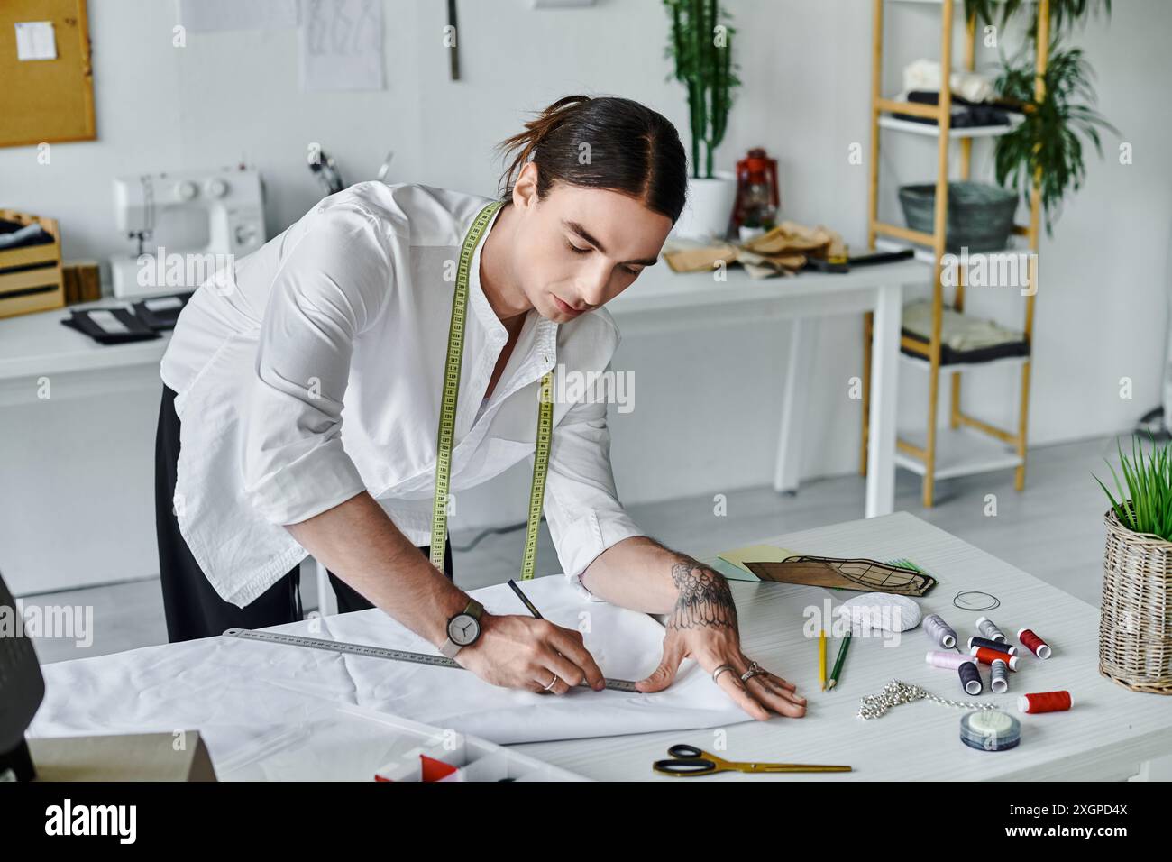 Un jeune homme mesure méticuleusement le tissu dans son atelier de restauration de vêtements DIY. Il se concentre sur la durabilité en donnant une nouvelle vie aux vêtements jetés. Banque D'Images