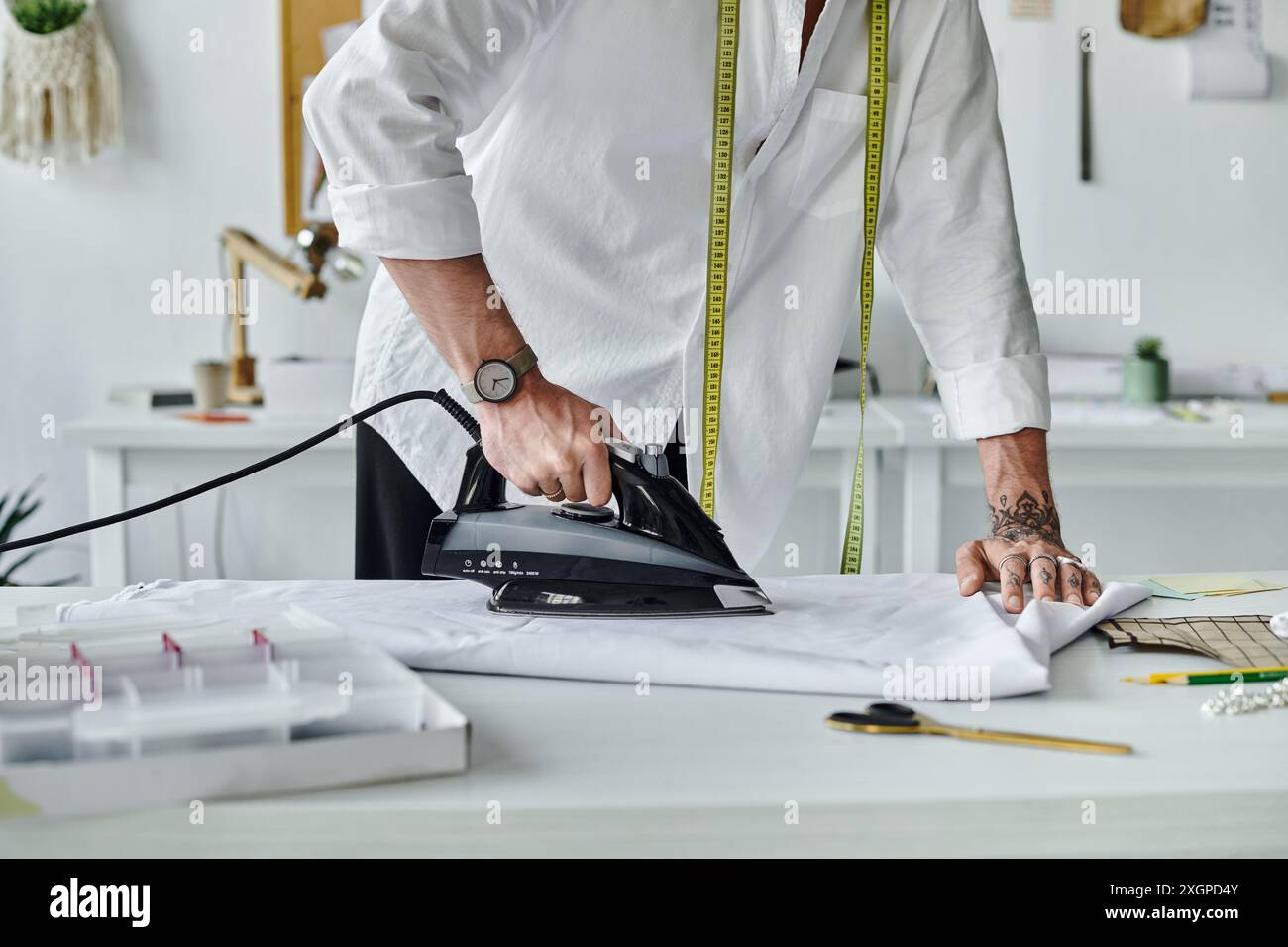 Un jeune homme repasse un vêtement dans son atelier, montrant sa passion pour la restauration durable des vêtements. Banque D'Images