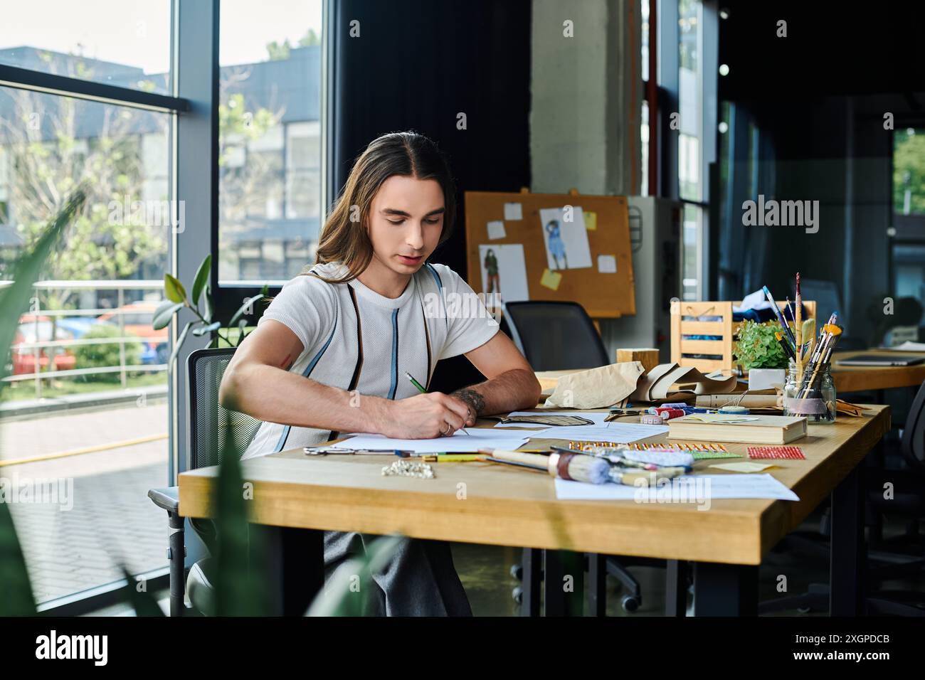 Un jeune homme dessine des dessins dans son atelier de restauration de vêtements DIY. Il se concentre sur donner une nouvelle vie aux vêtements jetés, en promouvant un fashi durable Banque D'Images