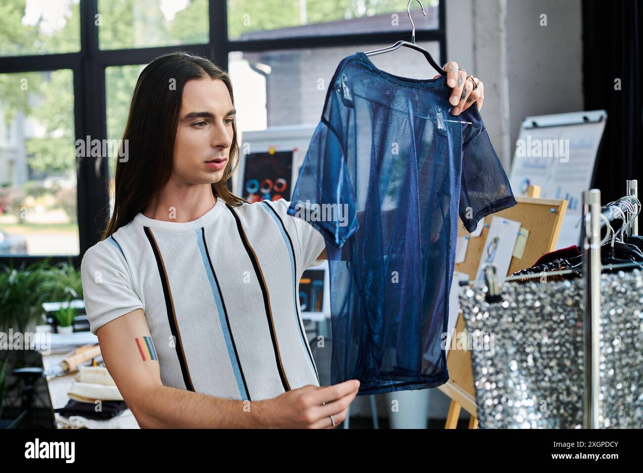 Un jeune homme examine un vêtement qu’il restaure dans son atelier de bricolage. Banque D'Images