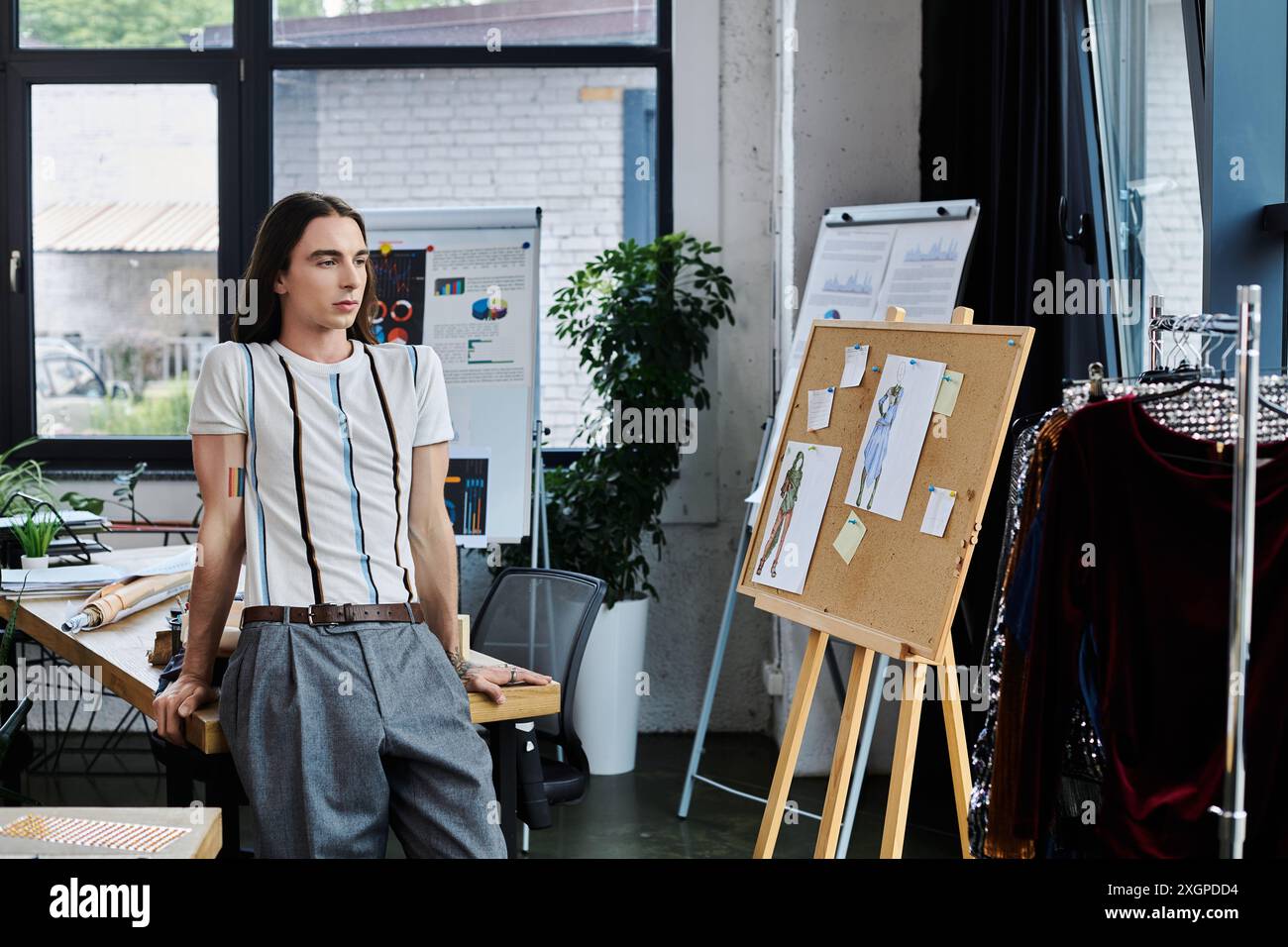 Un jeune homme gay se tient dans son atelier de restauration de vêtements DIY, axé sur la durabilité en donnant une nouvelle vie à des objets anciens. Banque D'Images