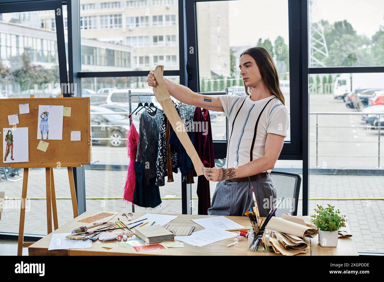 Un jeune homme mesure le tissu dans son atelier de restauration de vêtements, mettant en valeur sa passion pour la durabilité. Banque D'Images