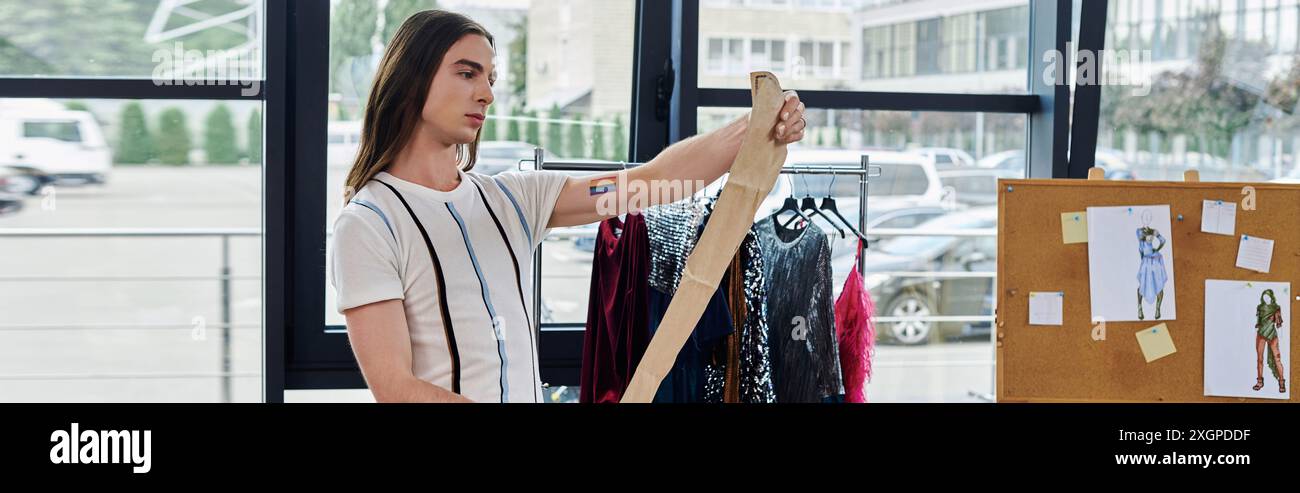 Un jeune homme examine le tissu pour un projet de restauration de vêtements durable dans son studio de ville. Banque D'Images