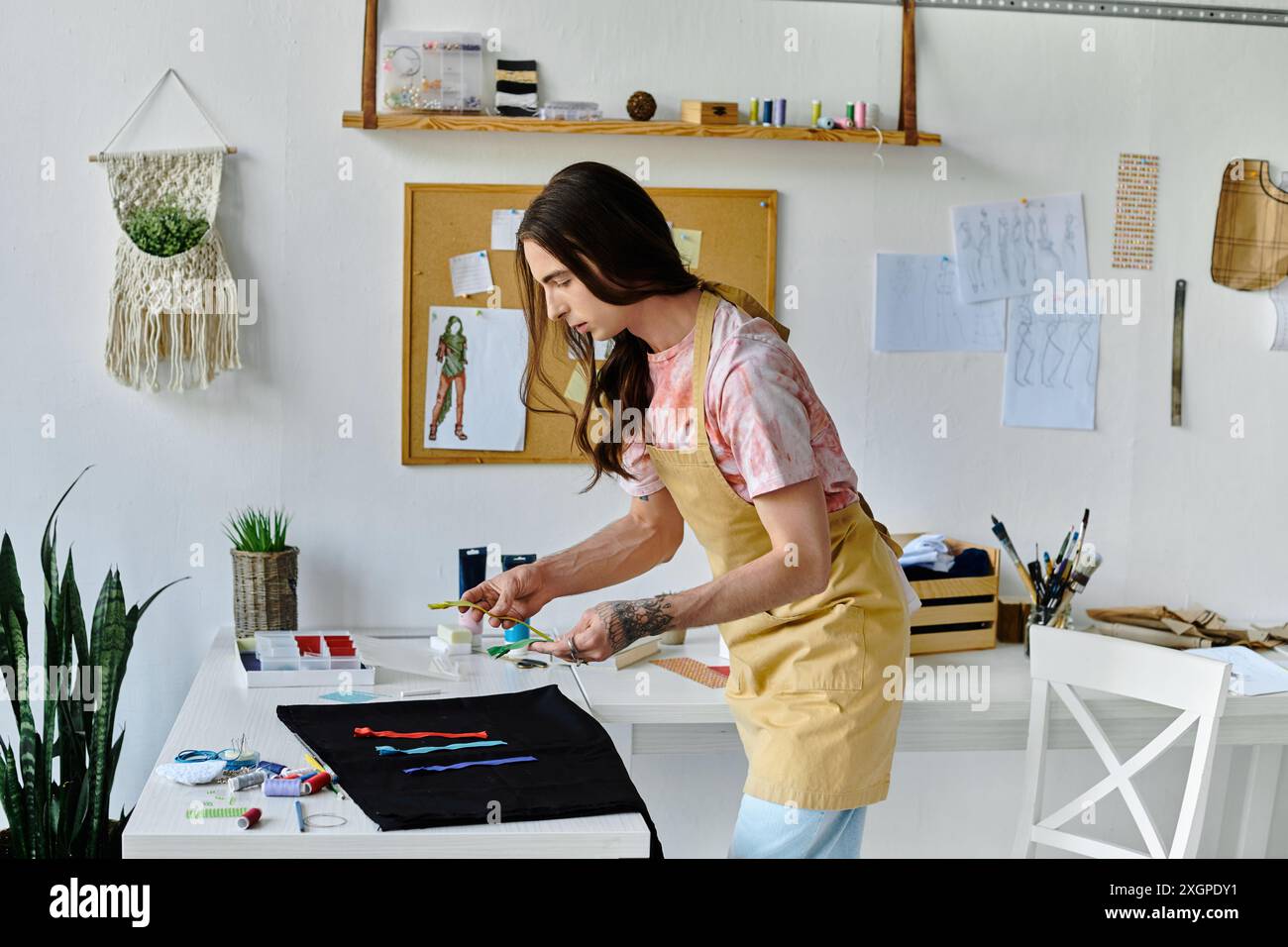Un jeune homme travaille dans son atelier de restauration de vêtements, montrant sa passion pour la mode durable et faisant revivre les vêtements jetés. Banque D'Images
