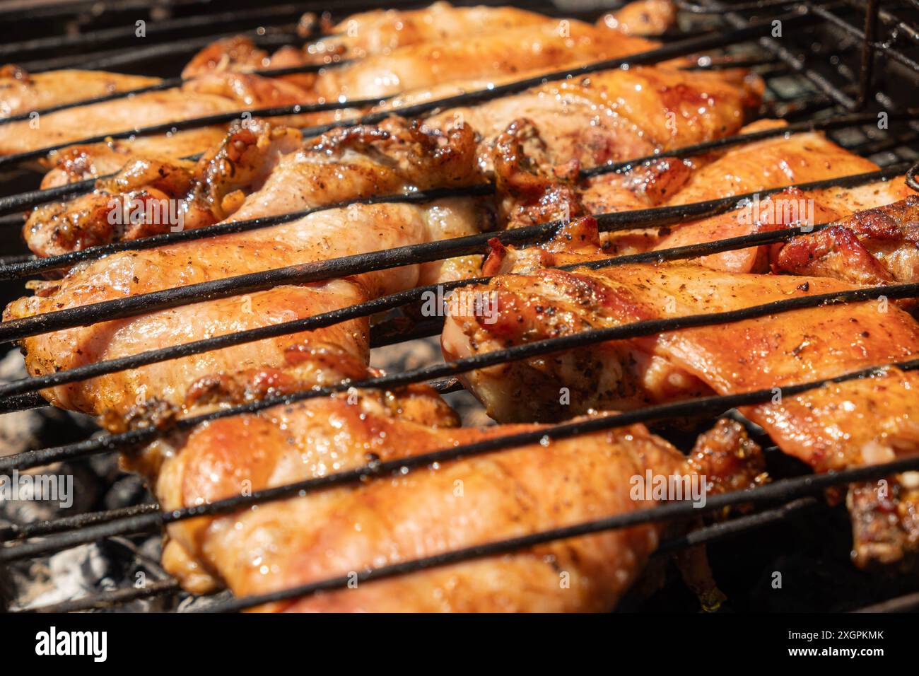 Gros plan de succulents morceaux de poulet assaisonnés grillés sur un barbecue, capturant la saveur délicieuse et fumée de la cuisine en extérieur. Banque D'Images