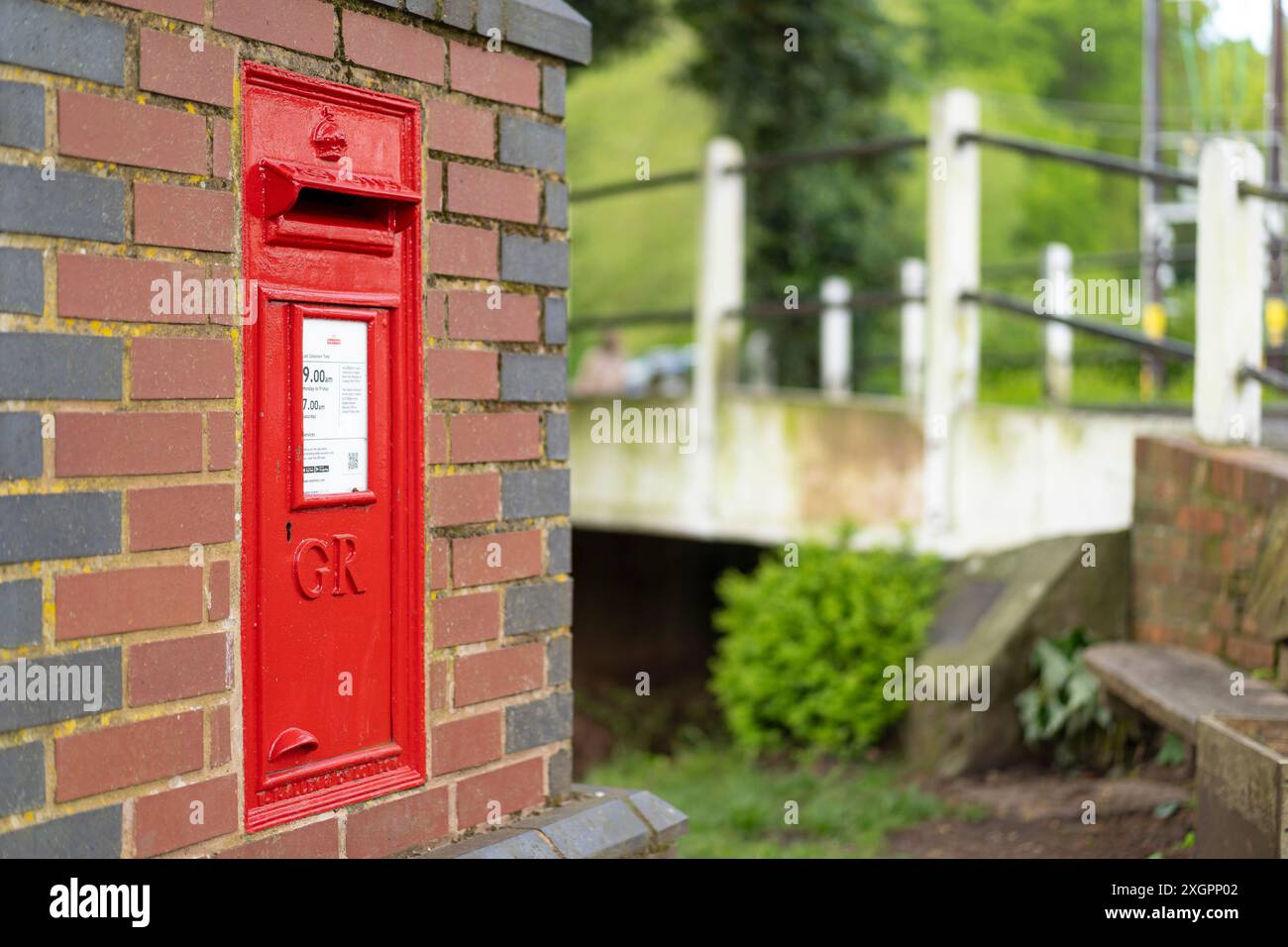 Gros plan d'une boîte postale/boîte aux lettres Royal mail rouge avec les lettres de chiffrement royales GR sur le devant, dans un mur de briques traditionnel à l'extérieur, Royaume-Uni. Banque D'Images