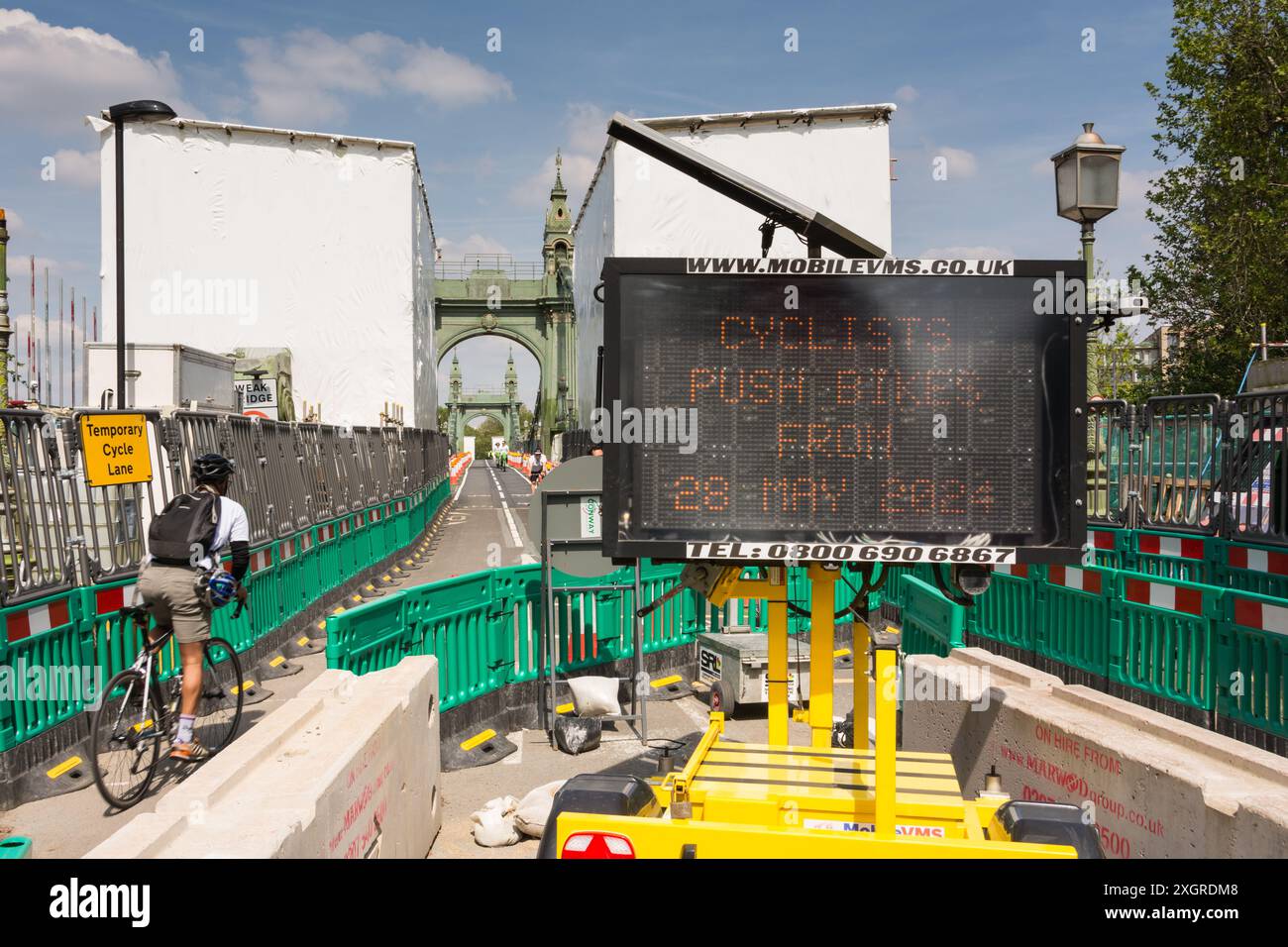Un cycliste masculin utilisant une voie cyclable temporaire pour traverser un pont Hammersmith encore fermé dans le sud-ouest de Londres, Angleterre, Royaume-Uni Banque D'Images