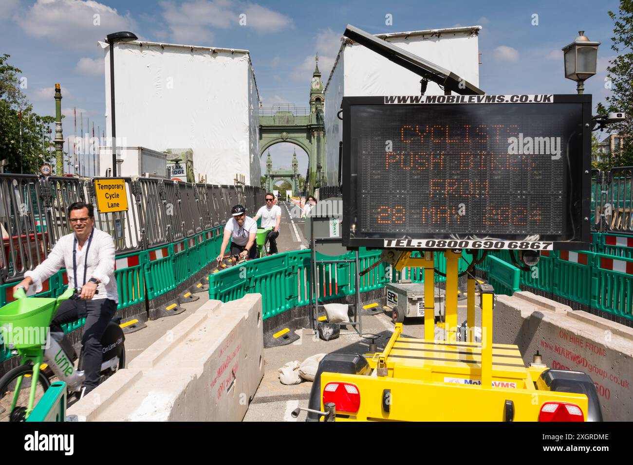 Cyclistes utilisant une voie cyclable temporaire pour traverser un pont Hammersmith encore fermé dans le sud-ouest de Londres, Angleterre, Royaume-Uni Banque D'Images
