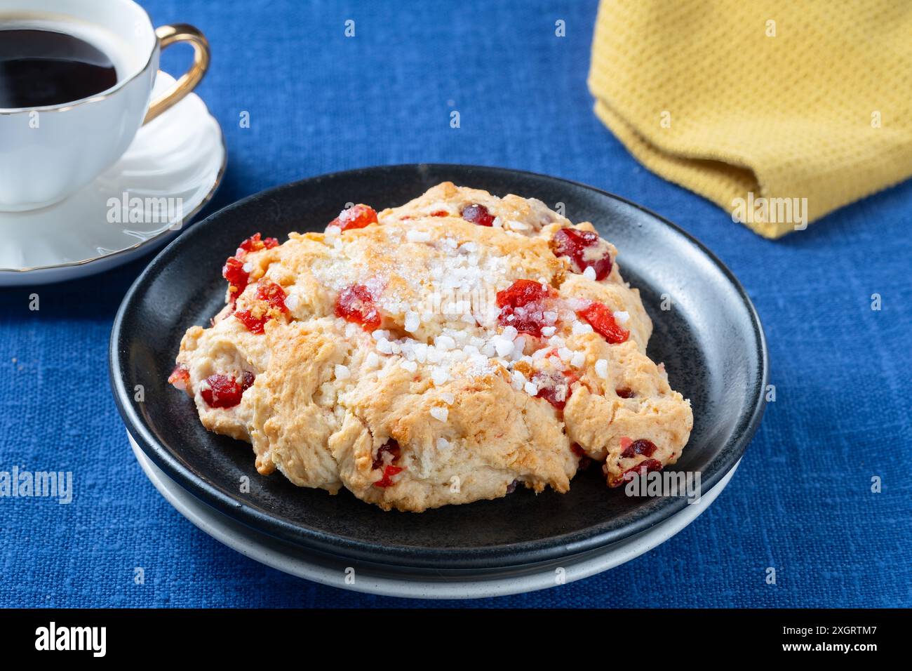 Un grand gâteau anglais frais et traditionnel Cherry Rock servi avec une tasse de café noir. Les gâteaux sont plaqués sur une nappe ordinaire Banque D'Images