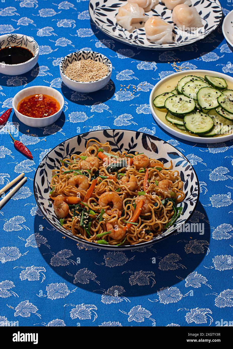 Vue de dessus d'une table animée avec cuisine chinoise, avec nouilles sautées avec crevettes et légumes dans un bol décoratif traditionnel, surroun Banque D'Images