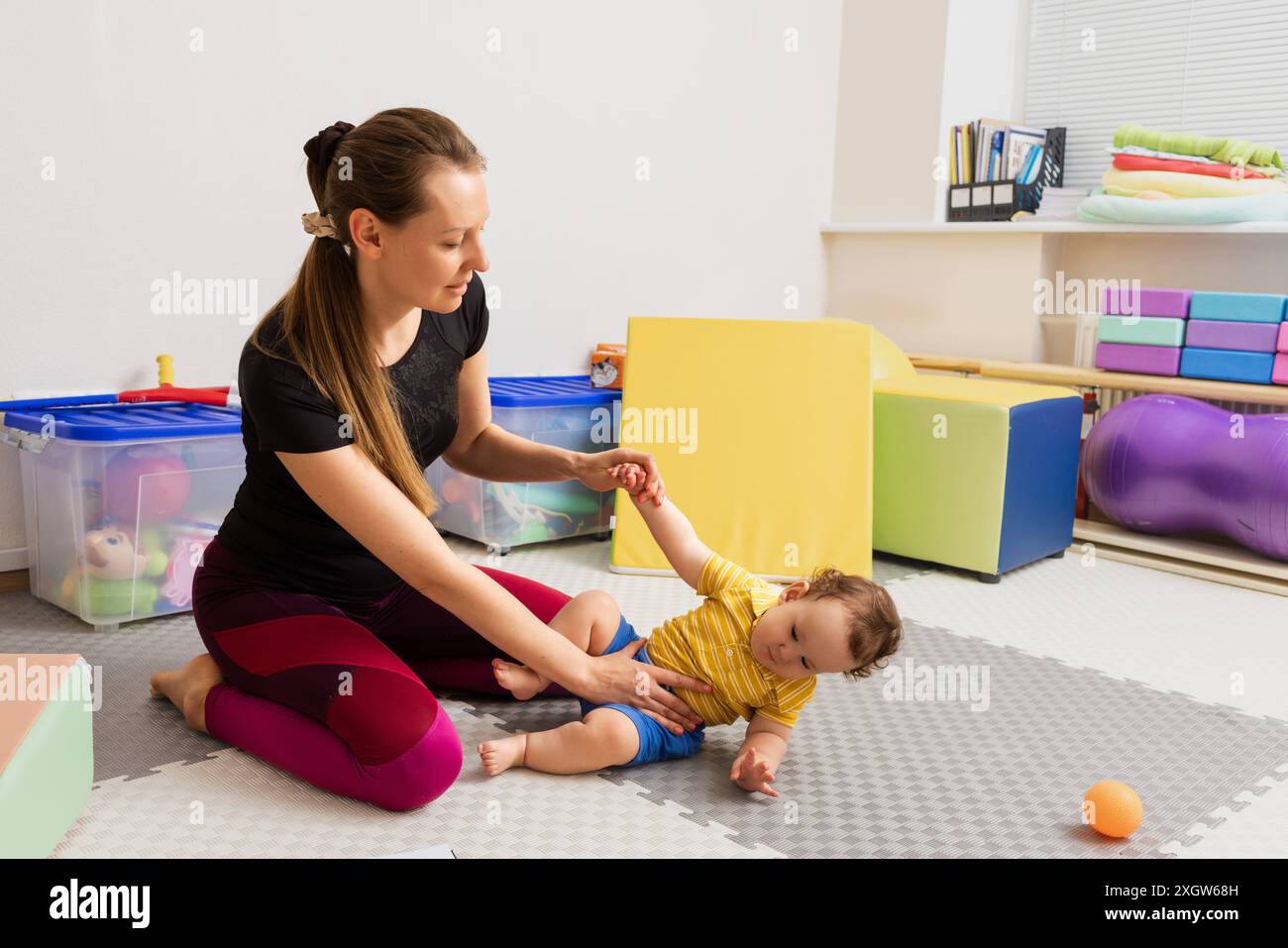 Physiothérapeute travaillant avec un bébé avec un tonus musculaire médiocre lors de l'examen neurologique du nourrisson dans la salle de thérapie. Réadaptation neurologique Banque D'Images