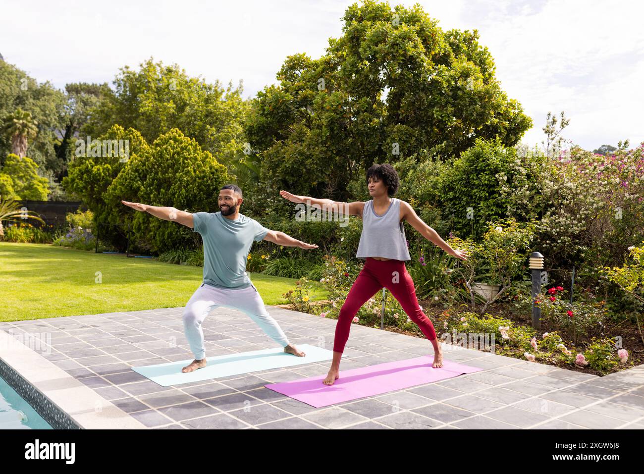 Couple biracial pratiquant le yoga en plein air, avec espace de copie. Ils profitent d'un style de vie sain dans un jardin serein. Banque D'Images