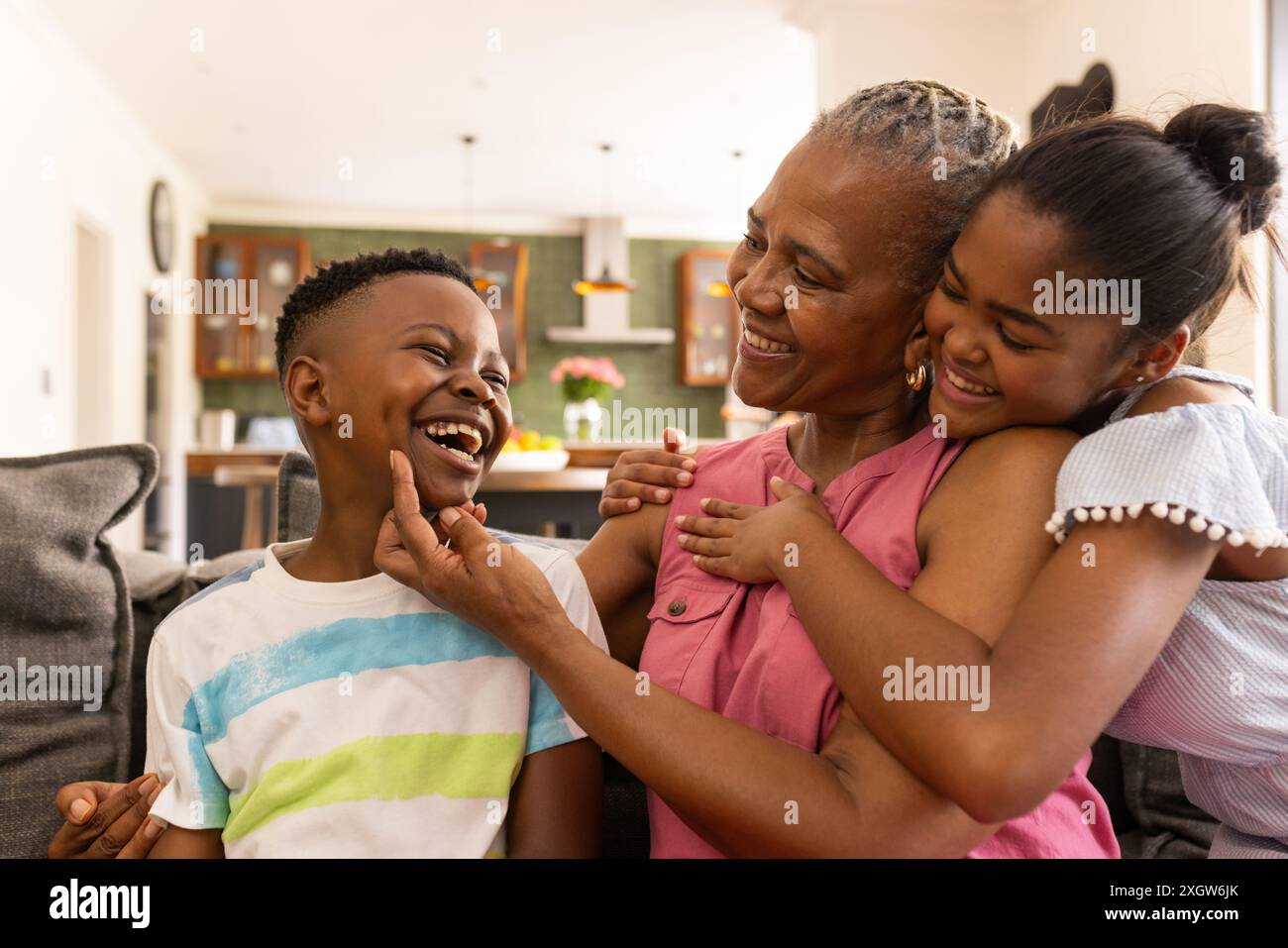 Senior afro-américaine profite d'un moment ludique à la maison avec ses petits-enfants. Leur rire crée une atmosphère chaleureuse et familiale dans le coz Banque D'Images