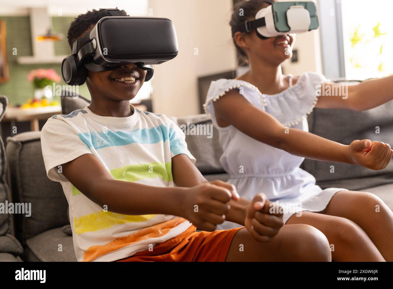 Frère biracial et sœur profiter des jeux VR à la maison. Ils sont plongés dans une expérience de réalité virtuelle, partageant un moment de joie et de divertissement. Banque D'Images
