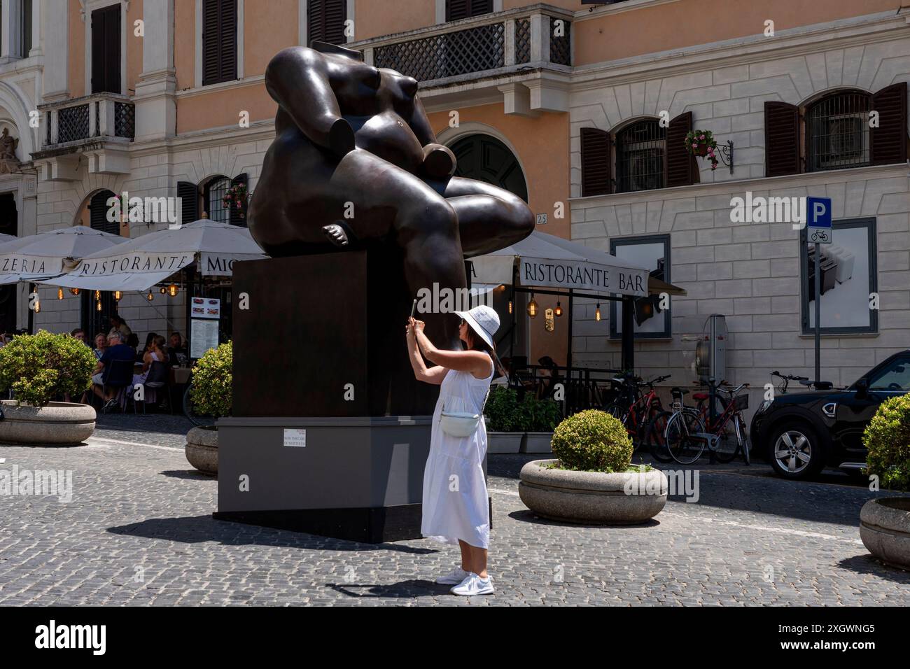 Tourist prend une photo en face de «femme assise» - une partie de «Botero a Roma» : un itinéraire d'exposition qui serpente dans les rues du centre-ville de Rome, combinant la beauté des œuvres de Fernando Botero avec la monumentalité de la capitale. La beauté contemporaine des sculptures de Fernando Botero complète le charme extraordinaire et unique de la capitale. L’exposition, qui s’étend sur quelques-unes des plus belles places du centre de Rome, permet de comparer deux mondes. Un hommage de la capitale au grand sculpteur colombien, récemment décédé, qui enrichit certains de ses plus R Banque D'Images