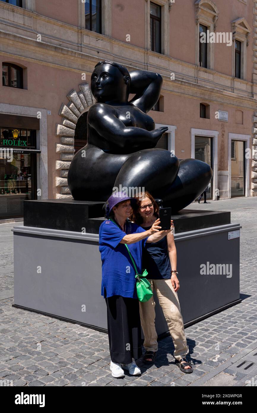 Rome, Italie. 10 juillet 2024. Les touristes prennent une photo devant ''˜Sitting woman' - partie de ''˜Botero a Roma' : un itinéraire d'exposition qui serpente dans les rues du centre-ville de Rome, combinant la beauté des œuvres de Fernando Botero avec la monumentalité de la capitale. La beauté contemporaine des sculptures de Fernando Botero complète le charme extraordinaire et unique de la capitale. L’exposition, qui s’étend sur quelques-unes des plus belles places du centre de Rome, permet de comparer deux mondes. Un hommage de la capitale au grand sculpteur colombien, récemment décédé Banque D'Images