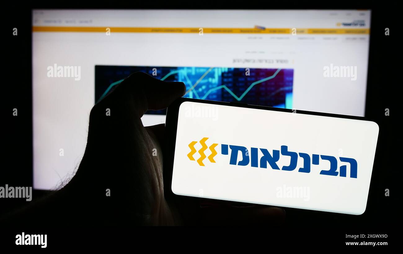Personne tenant le téléphone portable avec le logo de la société First International Bank of Israel Ltd (FIBI) devant la page Web. Concentrez-vous sur l'affichage du téléphone. Banque D'Images