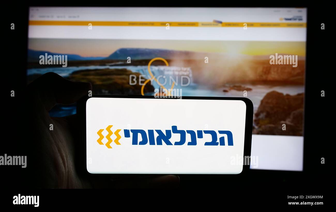 Personne tenant un téléphone portable avec le logo de la société First International Bank of Israel Ltd (FIBI) en face de la page Web. Concentrez-vous sur l'affichage du téléphone. Banque D'Images