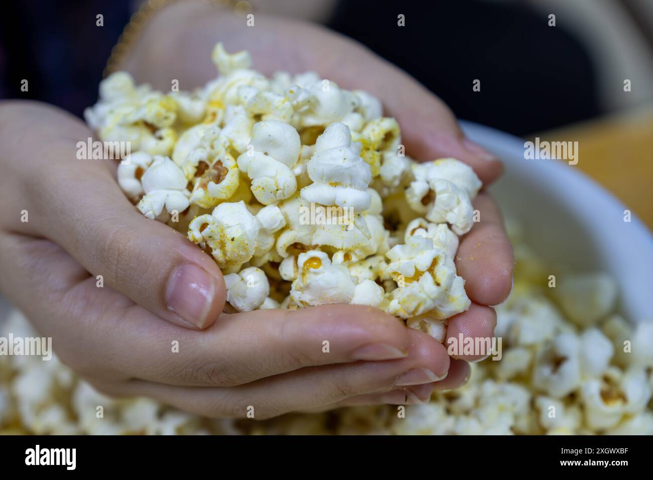 mains tenant un tas de pop-corn Banque D'Images