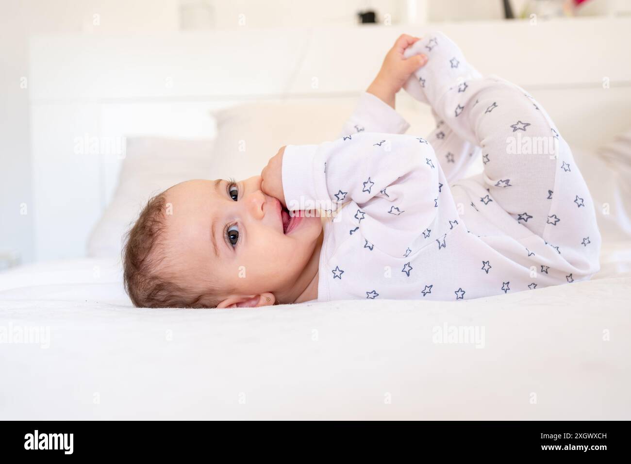 bébé nouveau-né souriant sur un lit blanc à la maison, le concept d'un bébé heureux et en bonne santé, un endroit pour le texte Banque D'Images