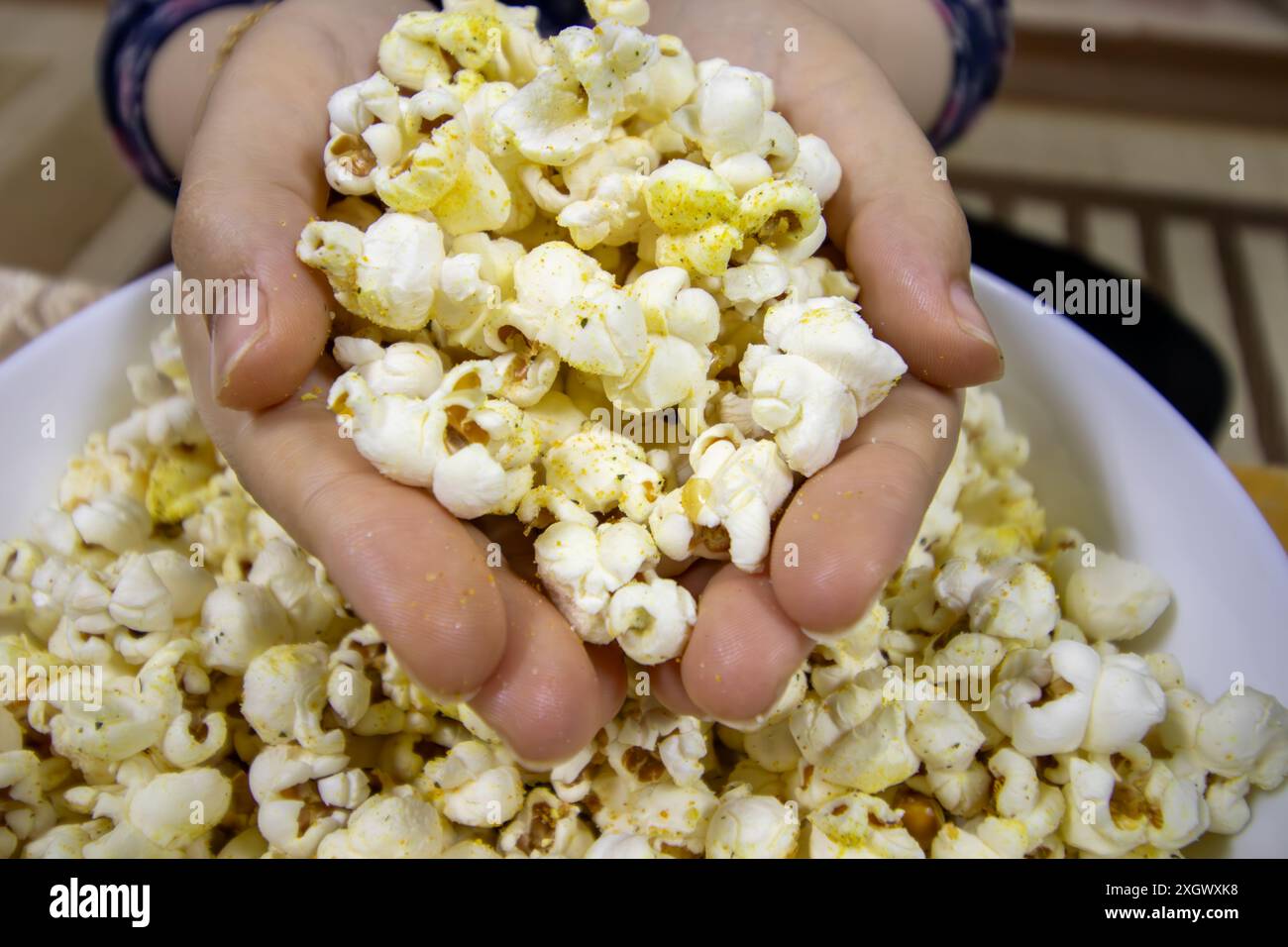 mains tenant un tas de pop-corn Banque D'Images