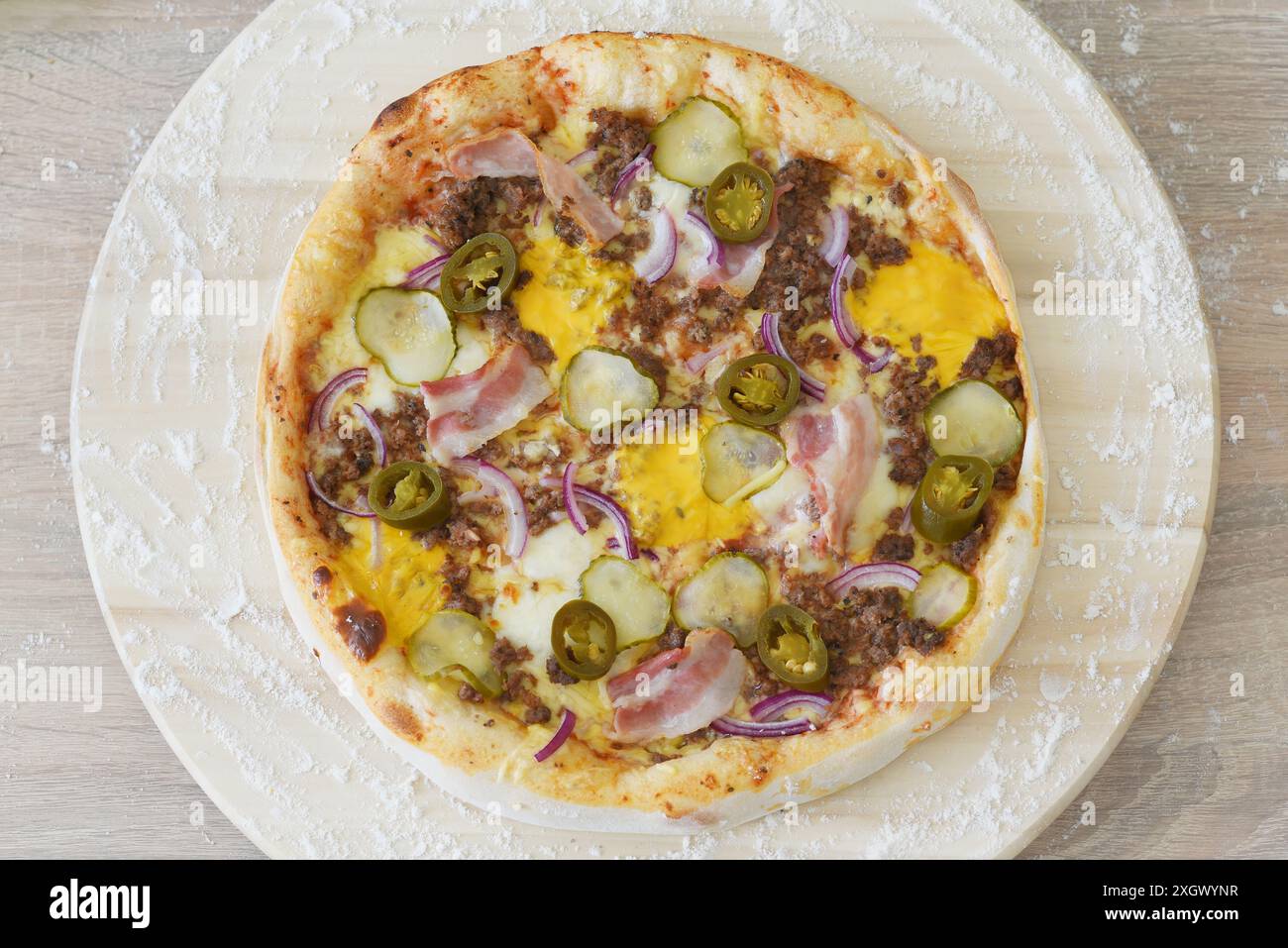 Vue de haut en bas d'une pizza fraîchement cuite avec diverses garnitures, y compris des champignons, du bacon et du fromage, servie sur du papier parchemin sur une surface en marbre. Banque D'Images