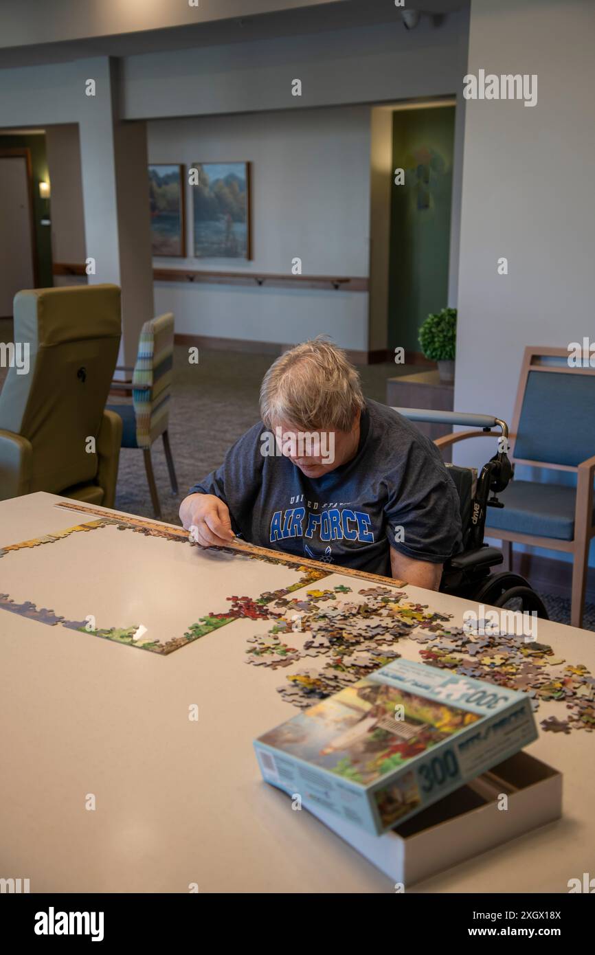 Maplewood, Minnesota. Femme âgée victime d'un accident vasculaire cérébral travaillant sur un puzzle dans la salle communautaire d'une maison de soins infirmiers. Banque D'Images