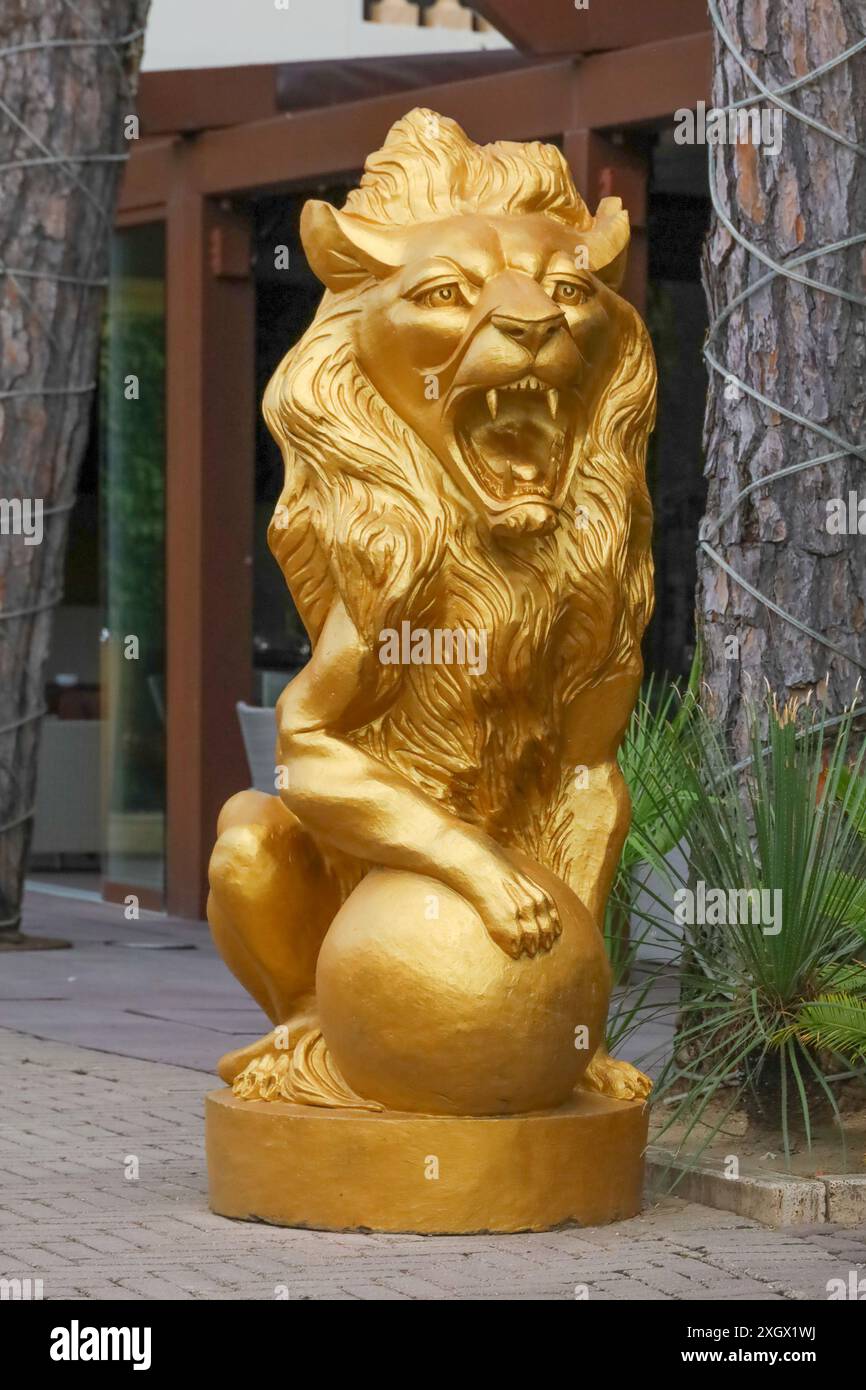 Statue de lion en or avec patte placée sur une sphère dorée. A l'extérieur d'un hôtel en Italie. Banque D'Images