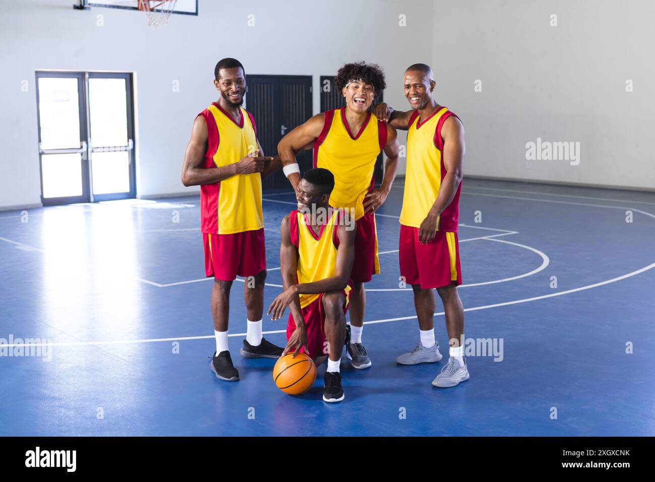 Divers joueurs de basket-ball, souriant à la caméra, posent sur le terrain. Leur sport et leur style de vie se mélangent tandis que l'esprit d'équipe brille, partageant un moment de camar Banque D'Images