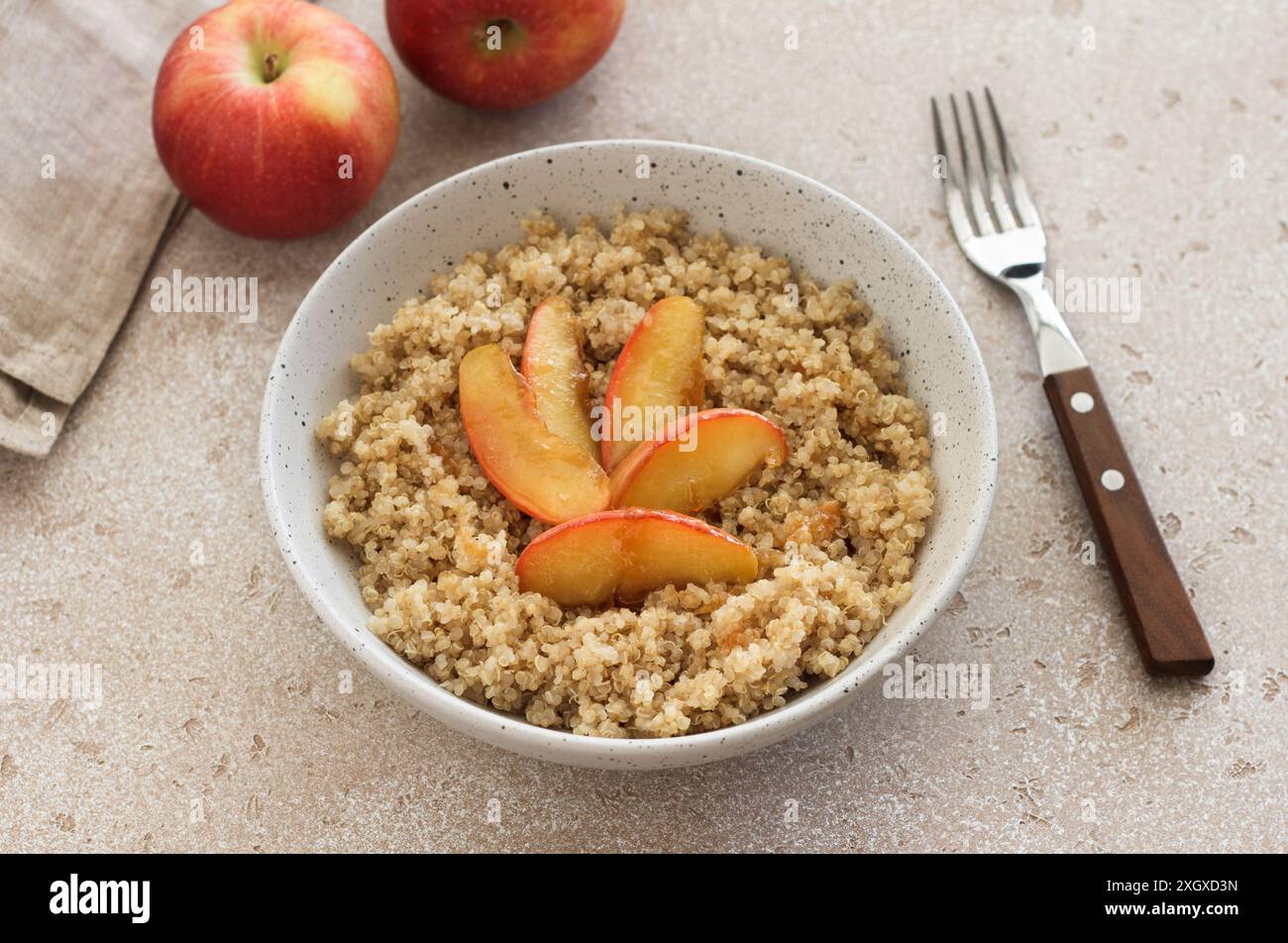 Quinoa avec tranche de pomme caramélisée sur un fond texturé beige. Plat sain végétalien Banque D'Images