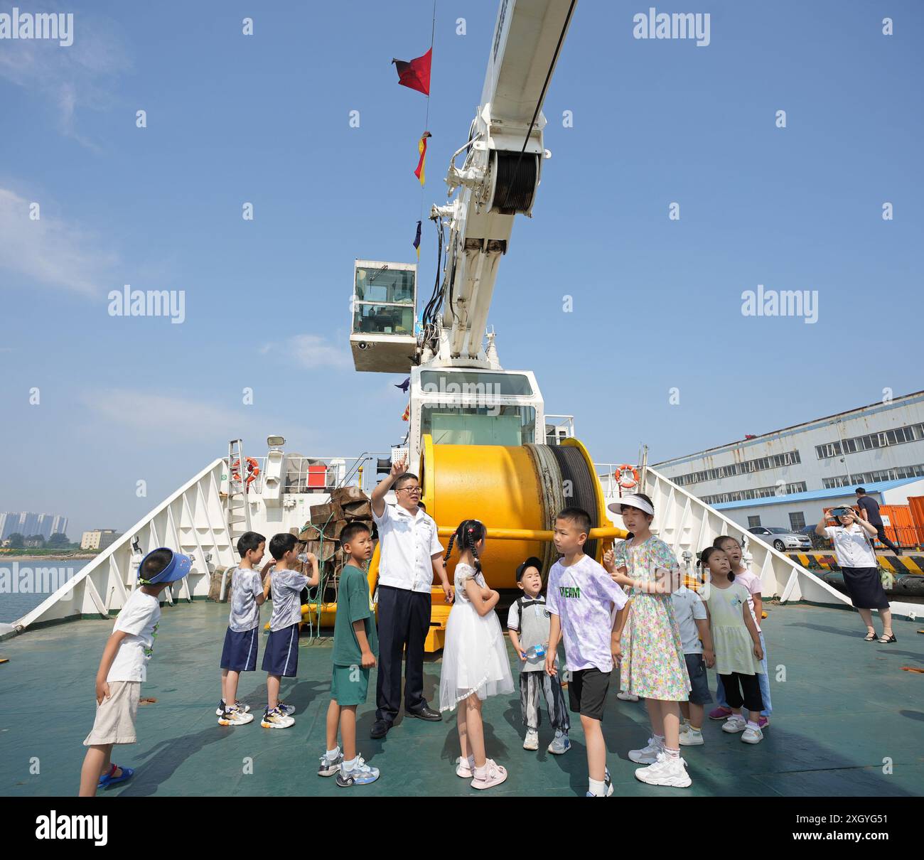 YANTAI, CHINE - 11 JUILLET 2024 - les enfants sont guidés par un membre d'équipage pour visiter le navire de navigation Haixun 153 au phare de navigation de Yantai Off Banque D'Images
