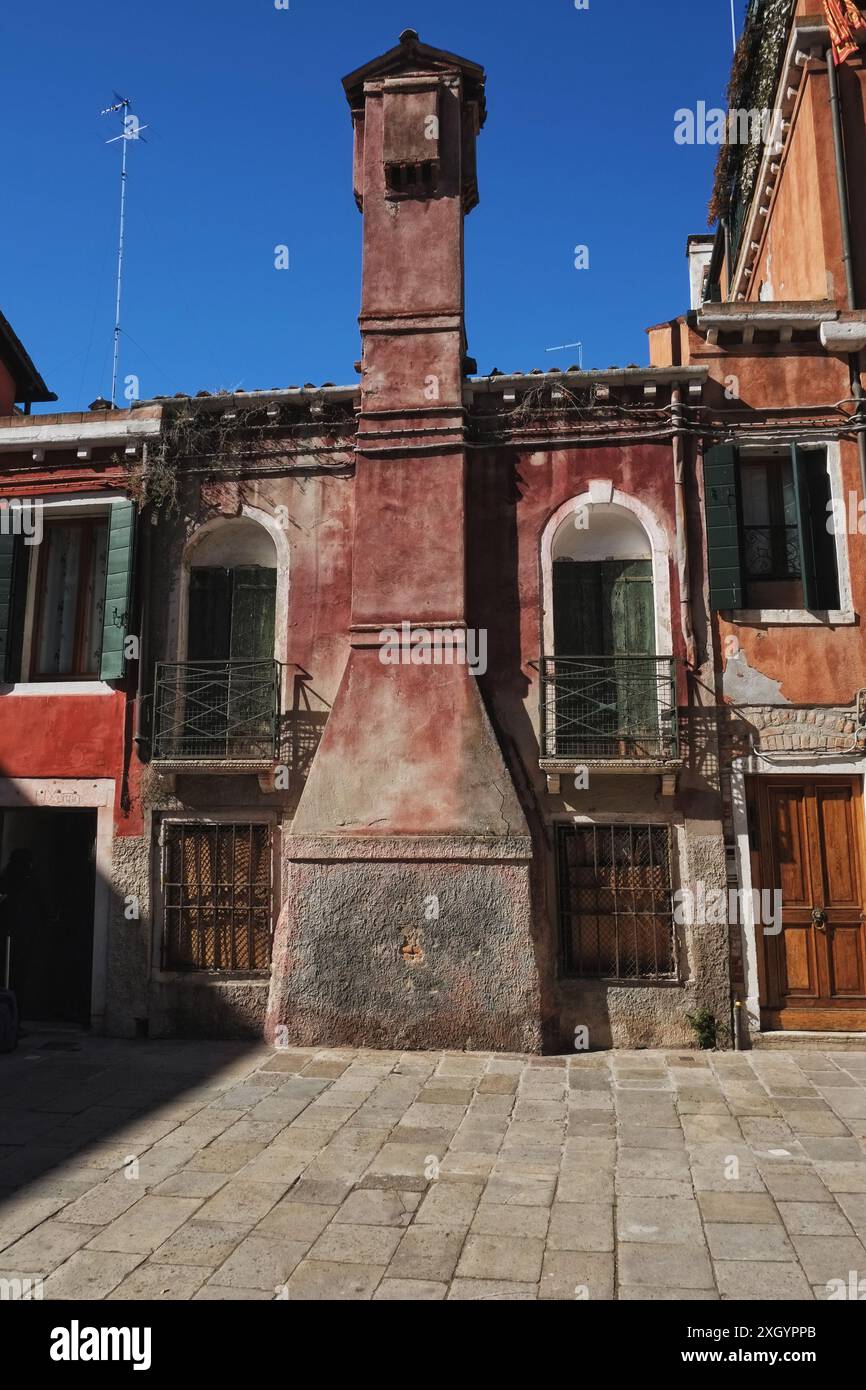 Une grande cheminée de style vénitien faisant saillie de l'avant d'une maison sur une place de dalle à Castello, arcs de balcons en retrait Juliette Banque D'Images
