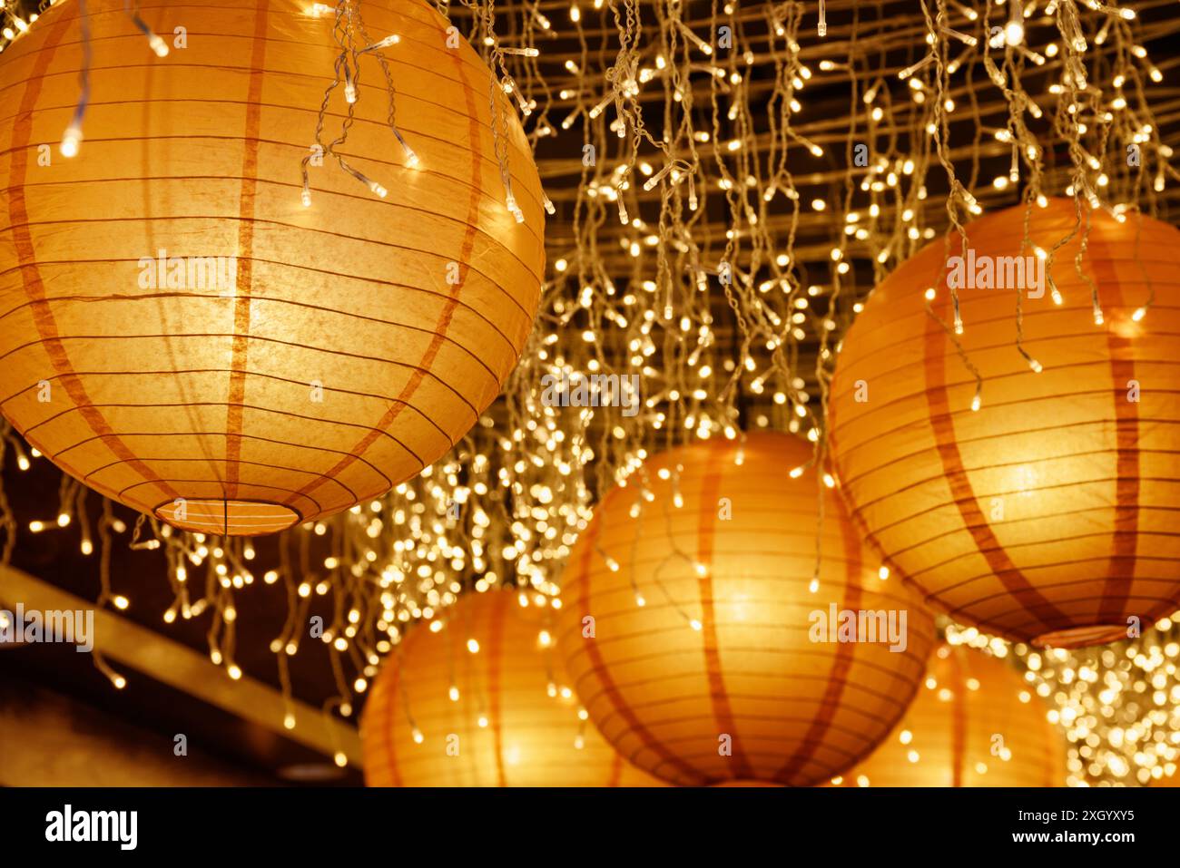 Belles lanternes en papier parmi les lumières blanches. Magnifique décoration. Banque D'Images