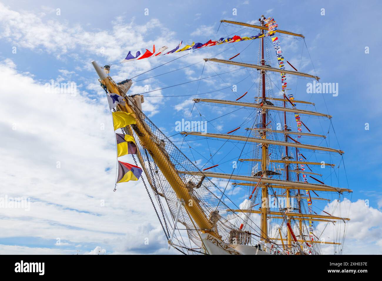 Mât de voilier avec drapeau nautique volant célébration décoration dans un ciel bleu ensoleillé et nuages, gréement de vieux grand voilier avec bu coloré Banque D'Images