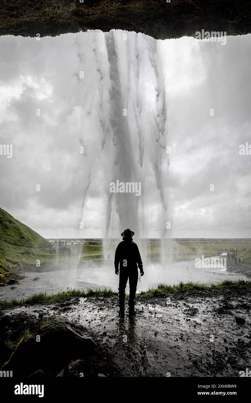 L'homme admire une puissante cascade Seljalandsfoss en islande par un jour nuageux Banque D'Images