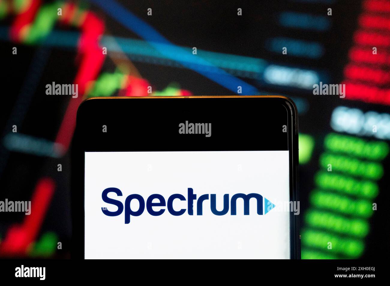 Dans cette illustration photo, la société américaine de télécommunications appartenant à Charter Communications, Spectrum (NASDAQ : CHTR), logo vu affiché sur un smartphone avec un graphique de l'indice boursier économique en arrière-plan. Banque D'Images