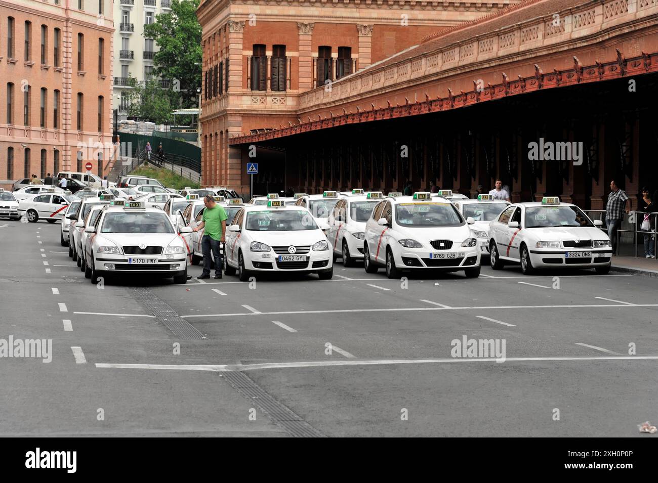 Gare d'Atocha, Madrid, Espagne, Europe, Une rangée de taxis blancs vous attend dans une rue de la ville devant un bâtiment historique Banque D'Images